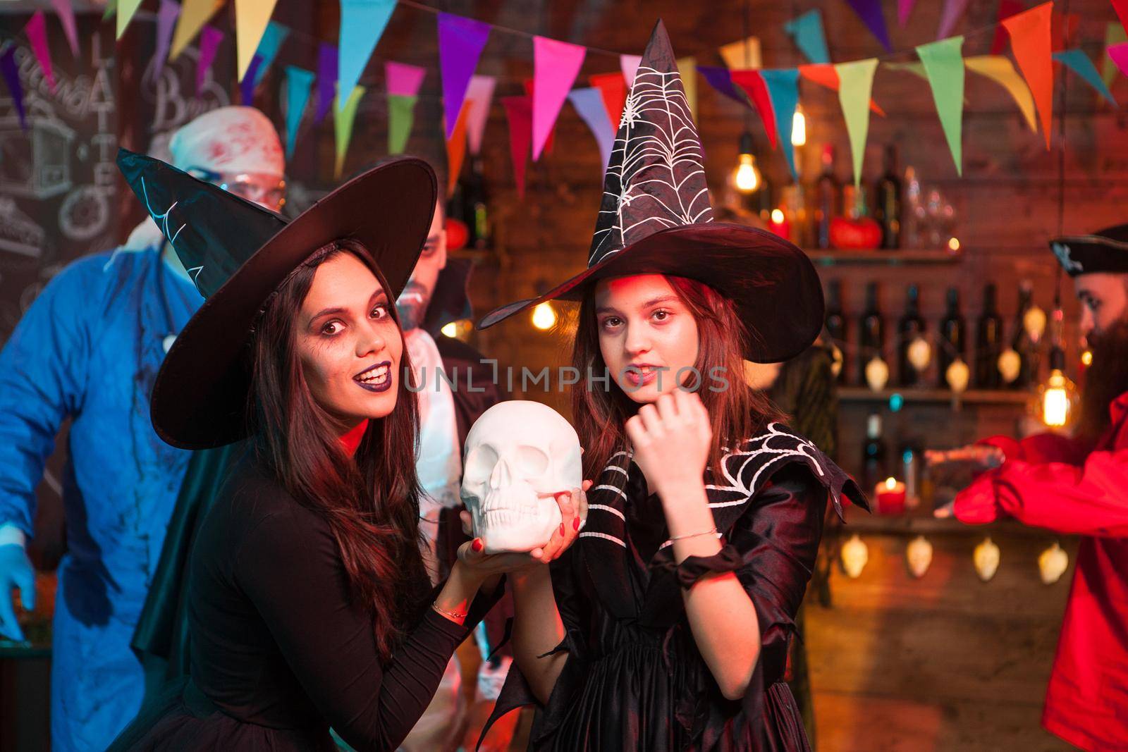 Beautiful young witches with big hats celebrating halloween by DCStudio