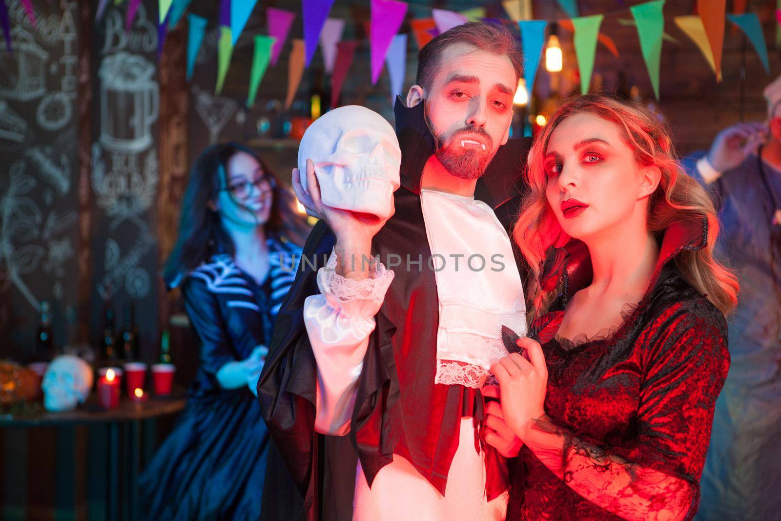 Sexy couple dressed up like vampires for halloween party. Beautiful woman dressed up like a vampire. Sexy man dressed up like Dracula.