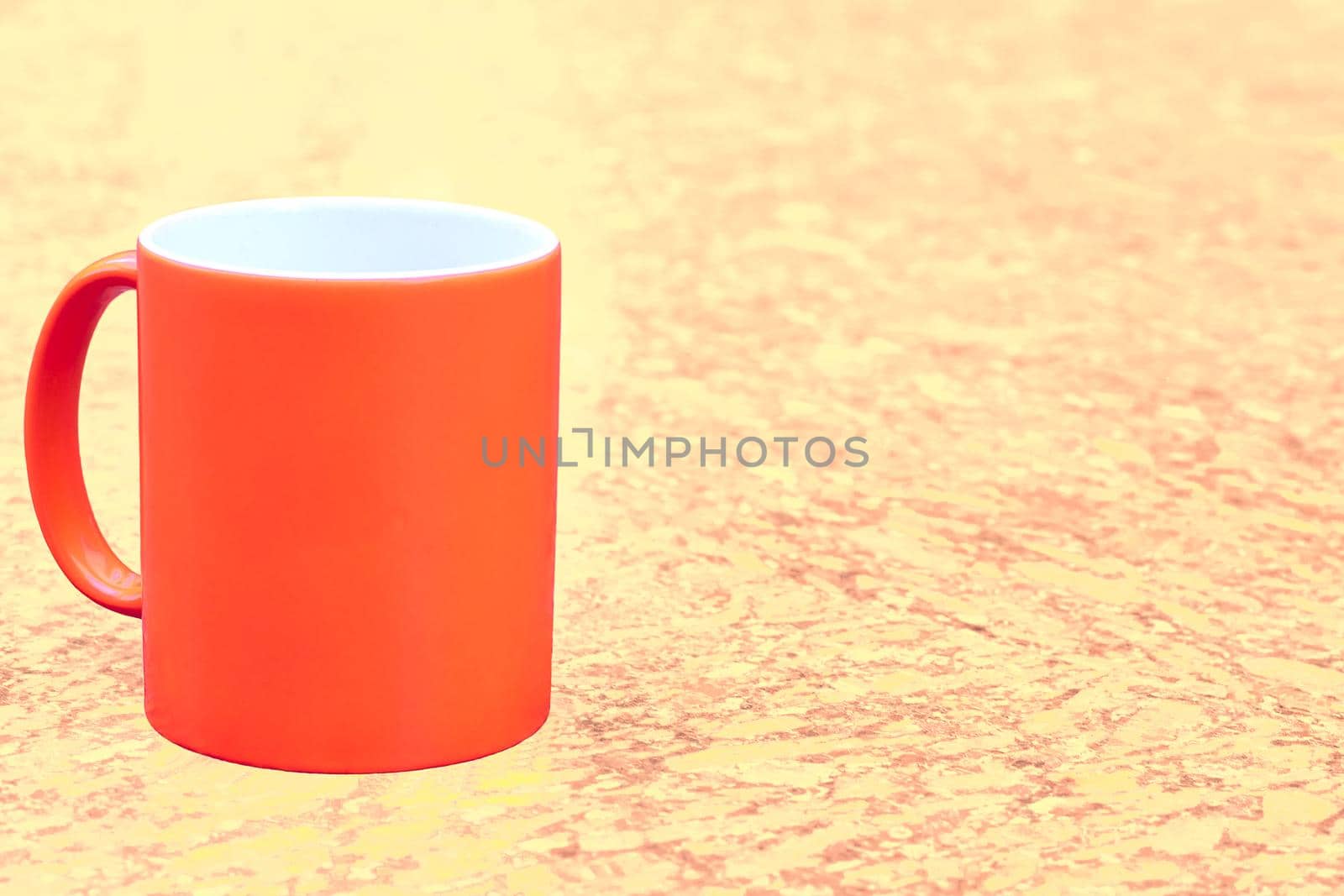 a small bowl-shaped container for drinking from, typically having a handle. Red ceramic cup mug on yellow brown spotted background. High quality photo