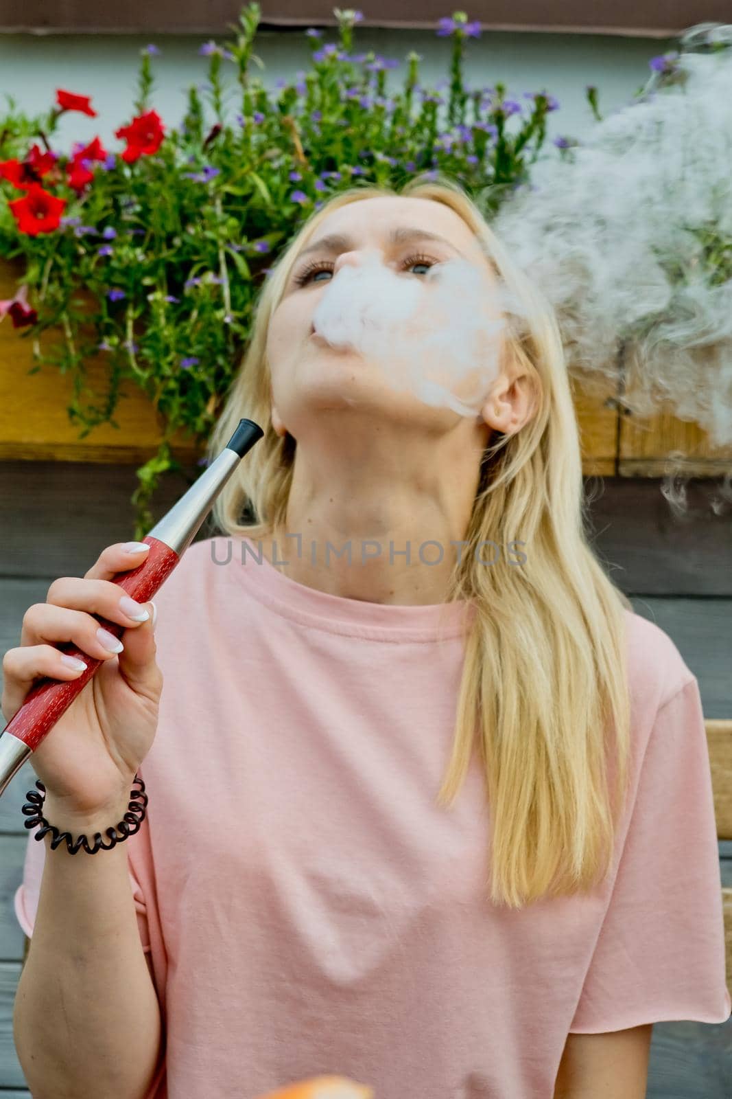 Young woman smokes a hookah in a restaurant. Portrait.