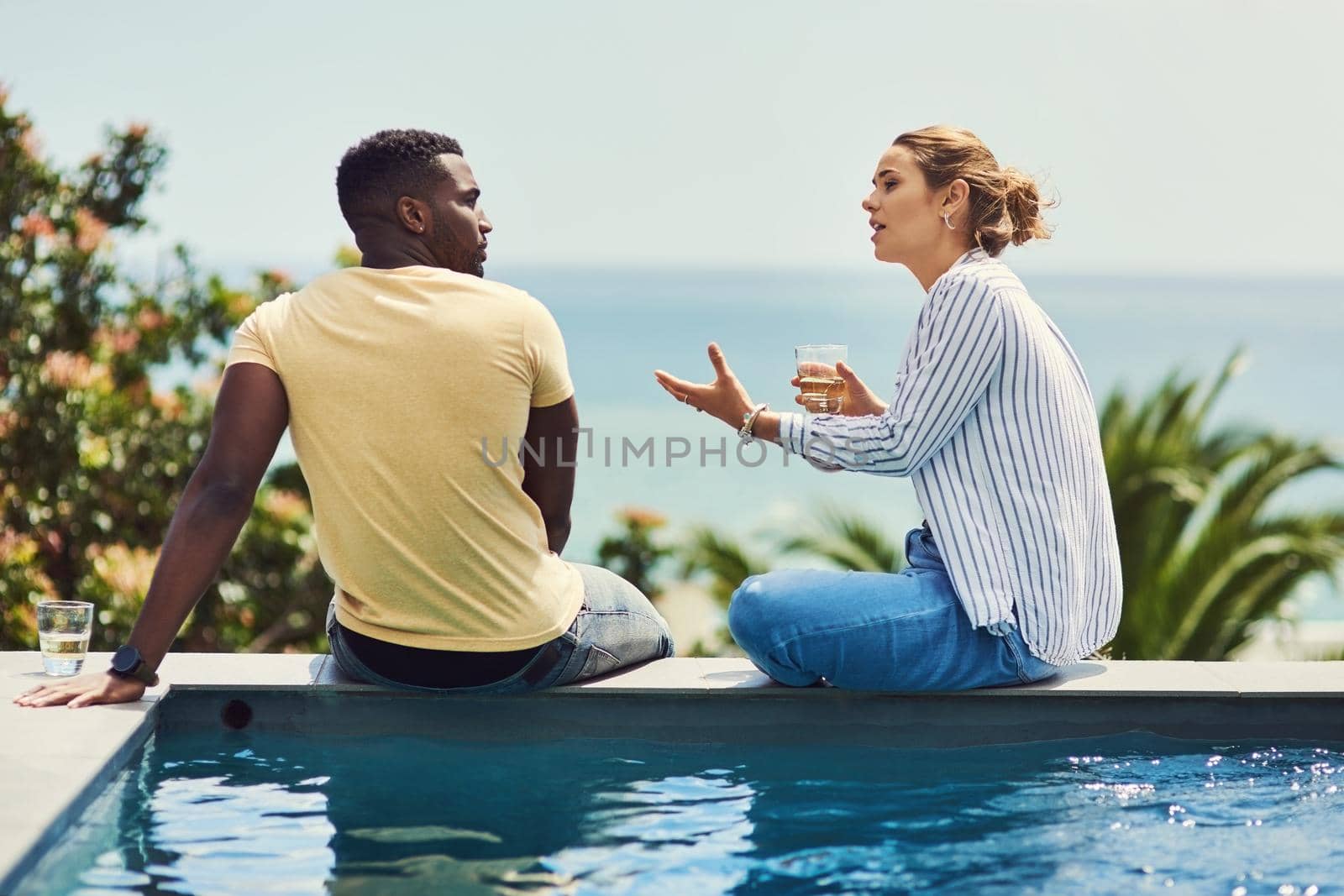 She always has a long story to tell. Rearview shot of a young couple enjoying drinks together while relaxing outdoors on holiday