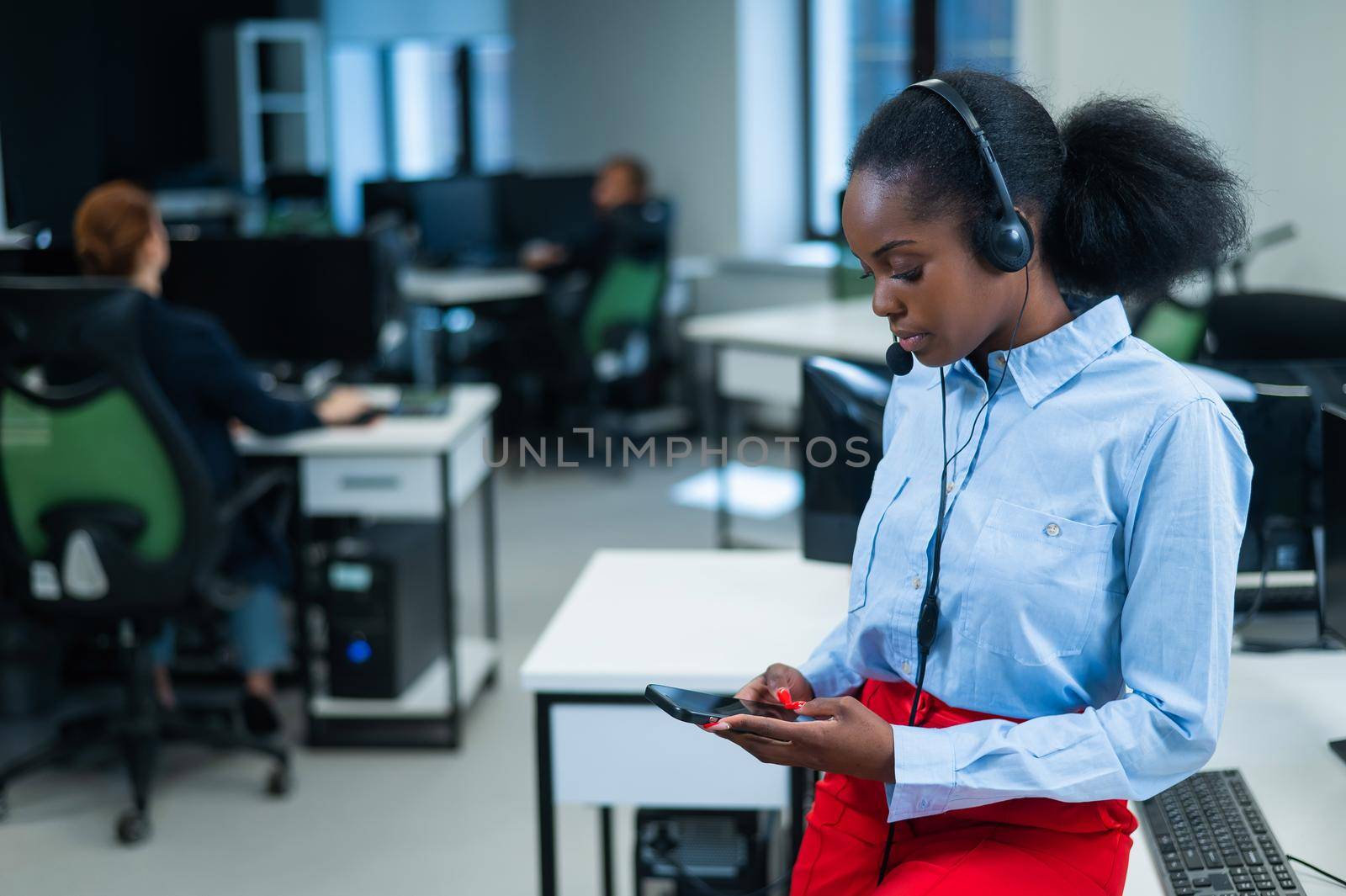 African female call center employee using smartphone