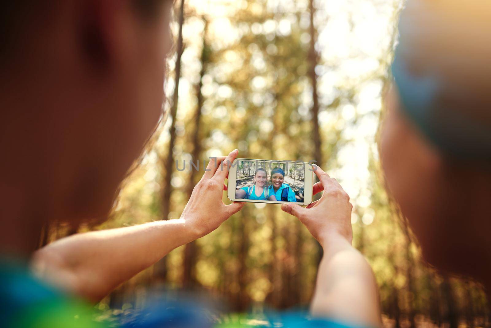 Selfies are a must. two sporty young woman taking pictures while out in nature. by YuriArcurs