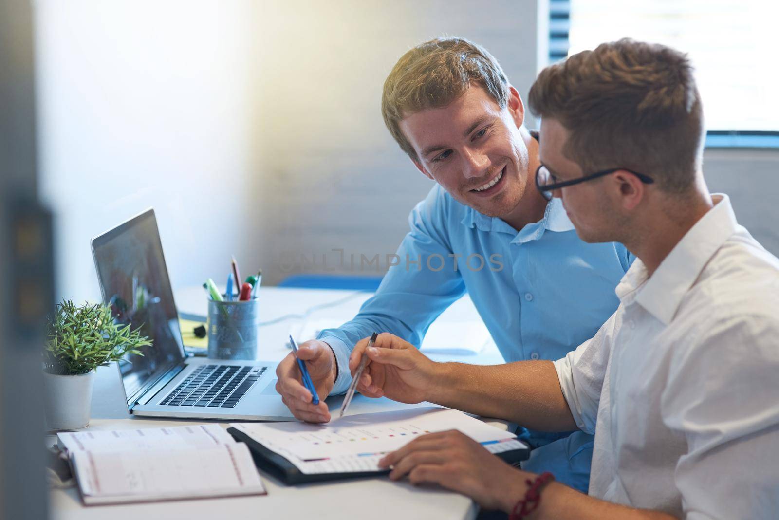 Good communication is key when working towards a common goal. two handsome young businessmen working together in their office