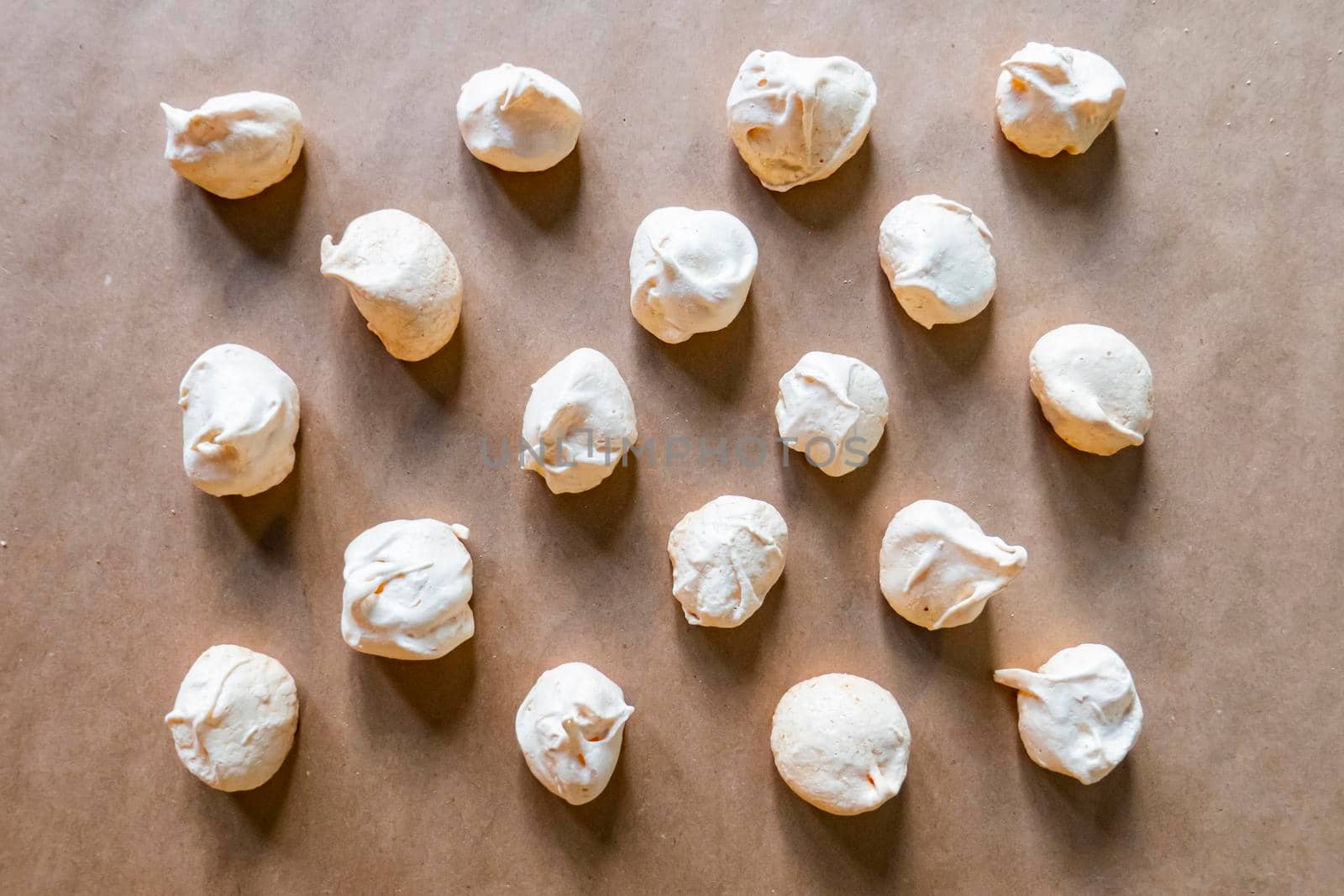 Sweets on a beautiful pastel surface in a minimalist style. Homemade meringues are lying on the baking paper. High quality photo