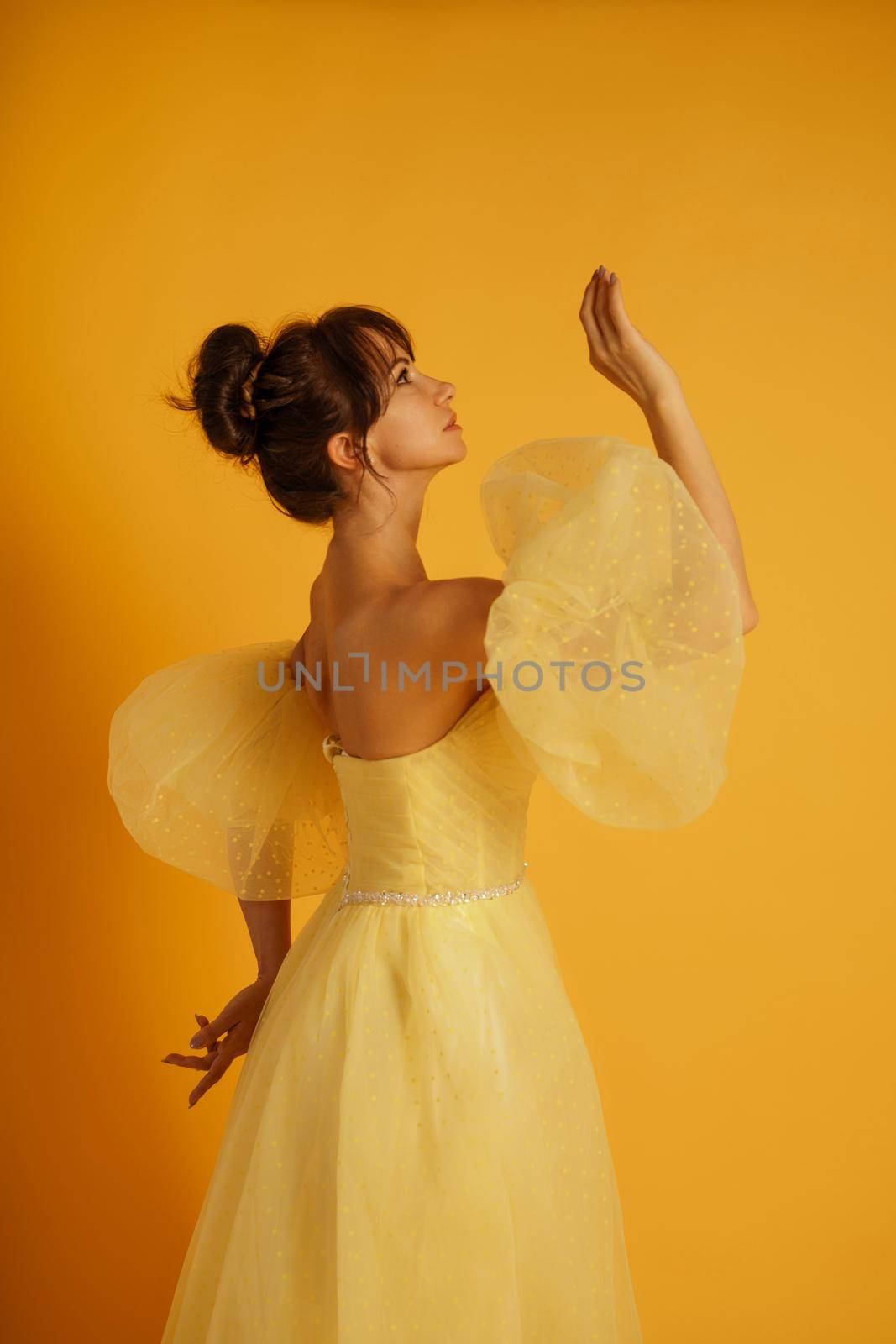 Profile portrait of a beautiful middle-aged woman in a yellow dress, her hair pulled up against a yellow background by Matiunina