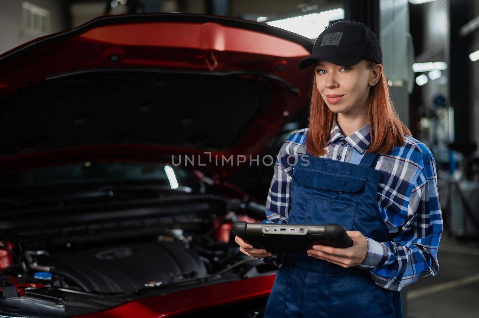 Caucasian female auto mechanic uses a special computer to diagnose faults