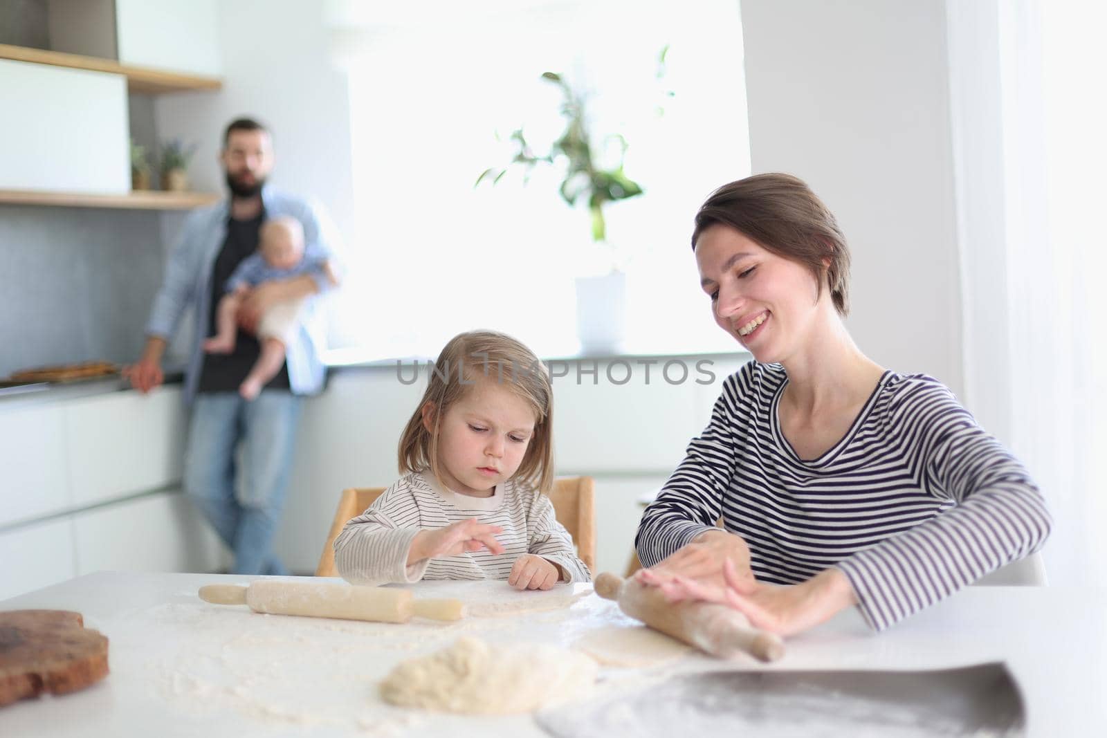 Happy parents playing with their children in the kitchen
