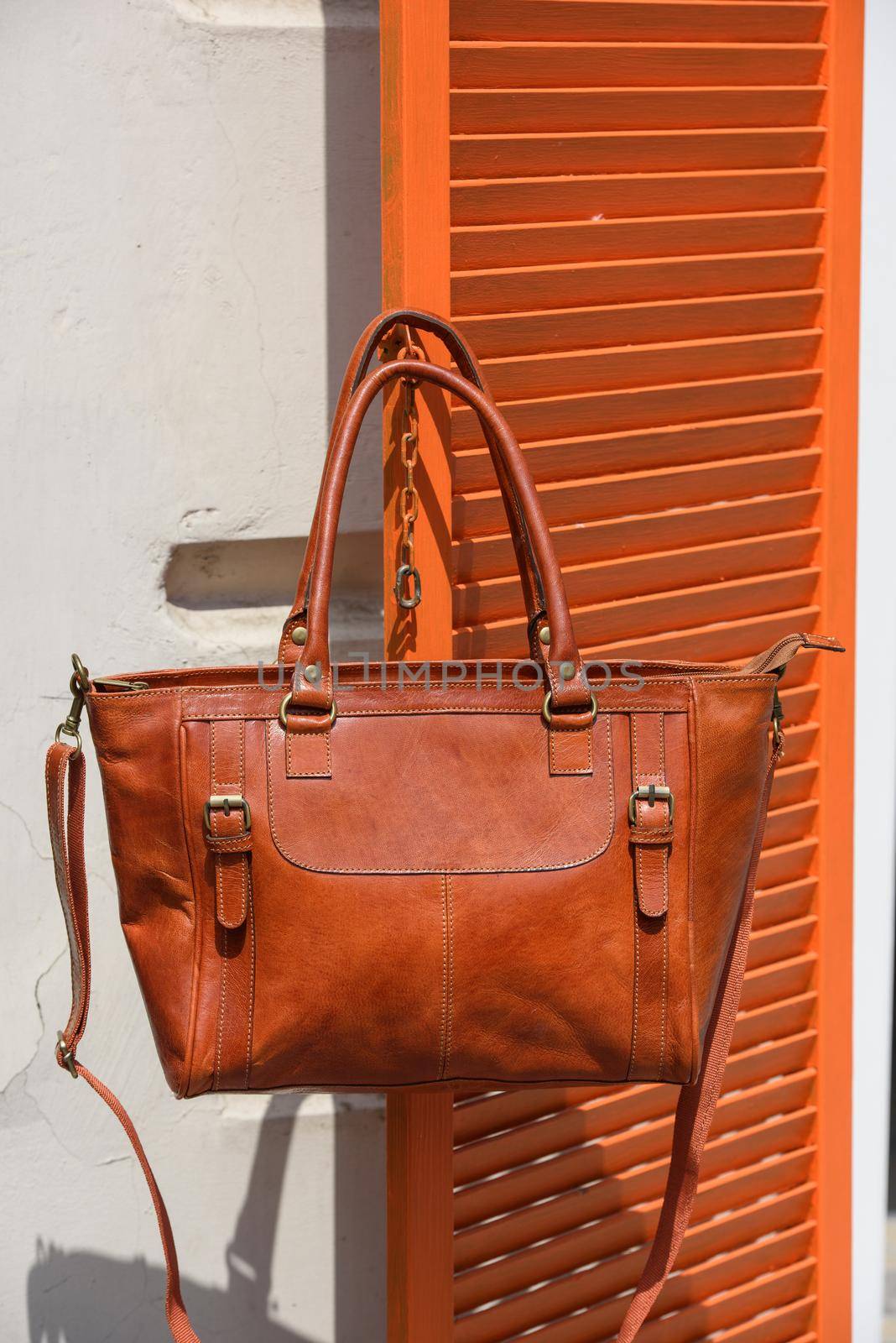 close-up photo of orange leather bag on a wooden blinds. outdoors photo