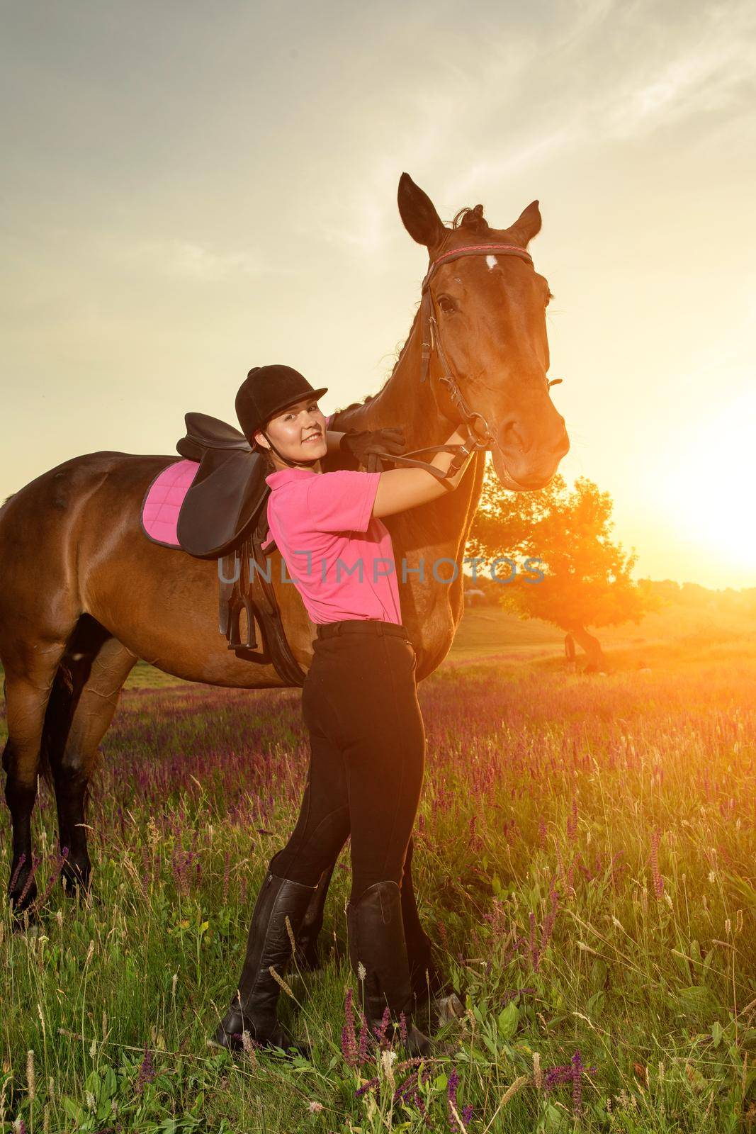 Beautiful young girl smile at her horse dressing uniform competition: outdoors portrait on sunset. Taking care of animals, love and friendship concept.