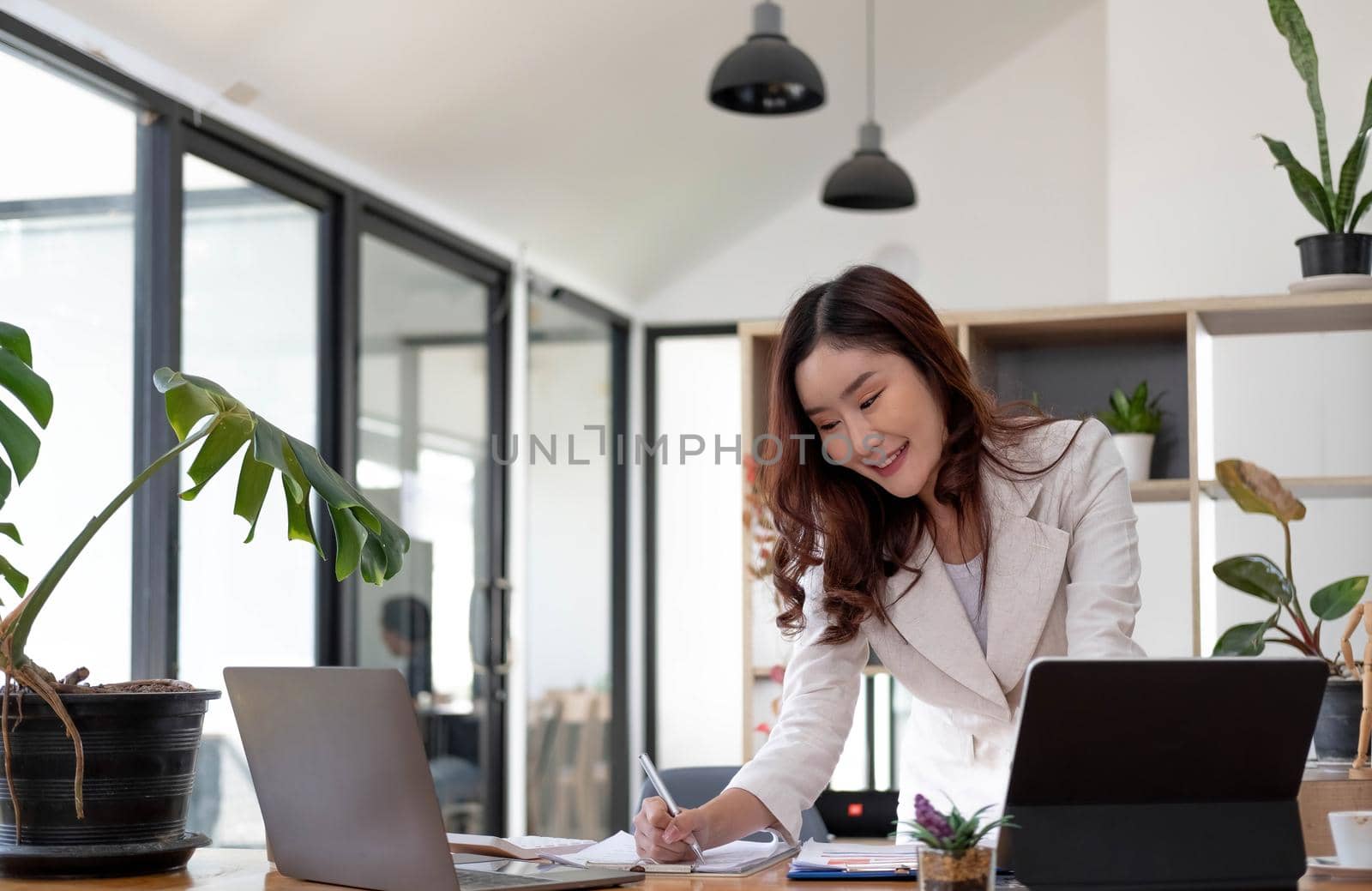 Asian Businesswoman Using laptop computer and working at office with calculator document on desk, doing planning analyzing the financial report, business plan investment, finance analysis concept..