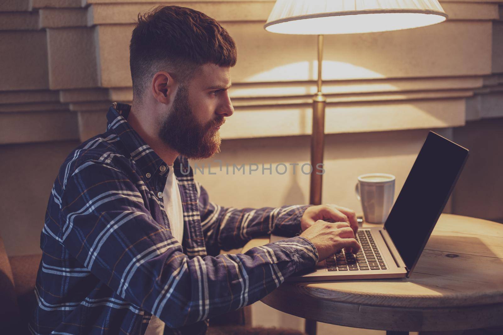 Young professional surfing the Internet on his laptop in a cafe by nazarovsergey