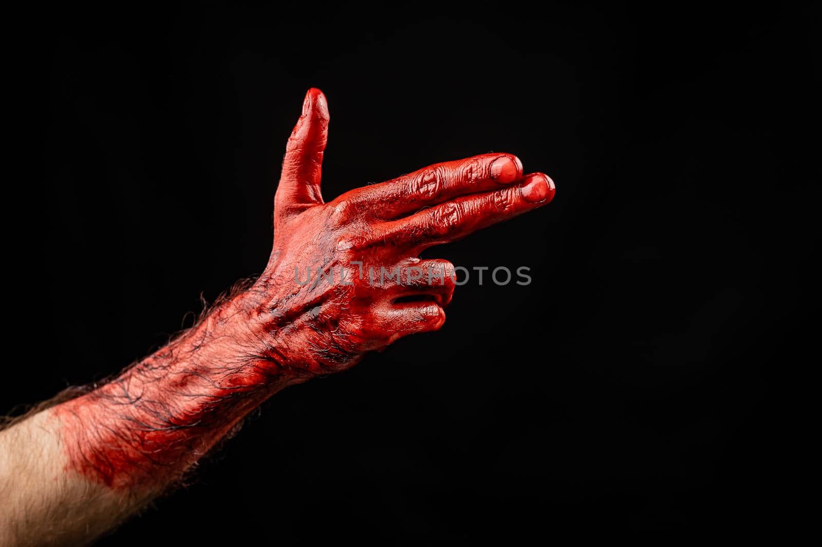 Bloody male hand gesturing shows a gun against black background. by mrwed54