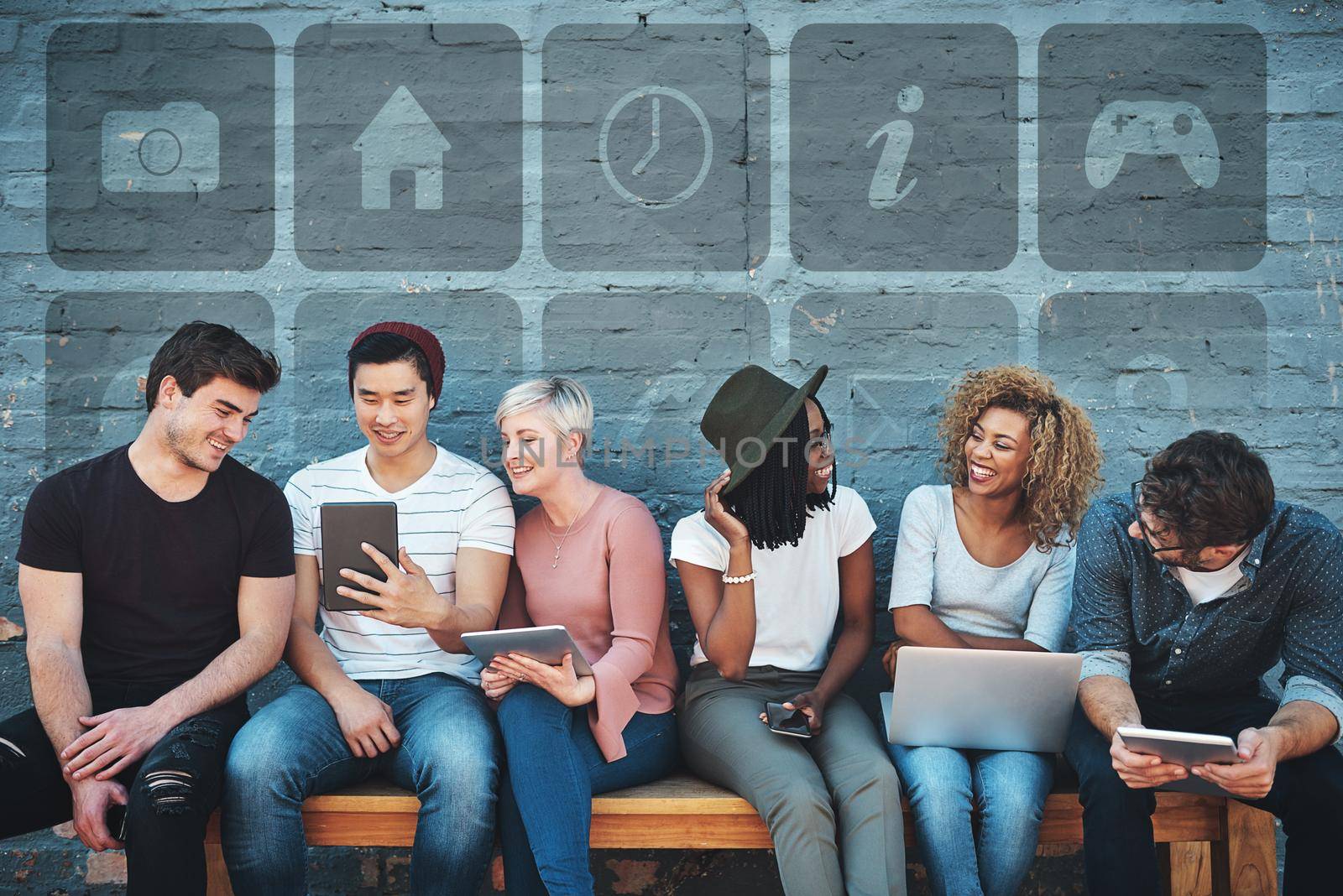 We stay connected everywhere we go. a group of cheerful creative businesspeople using their digital devices while sitting on a bench together outdoors