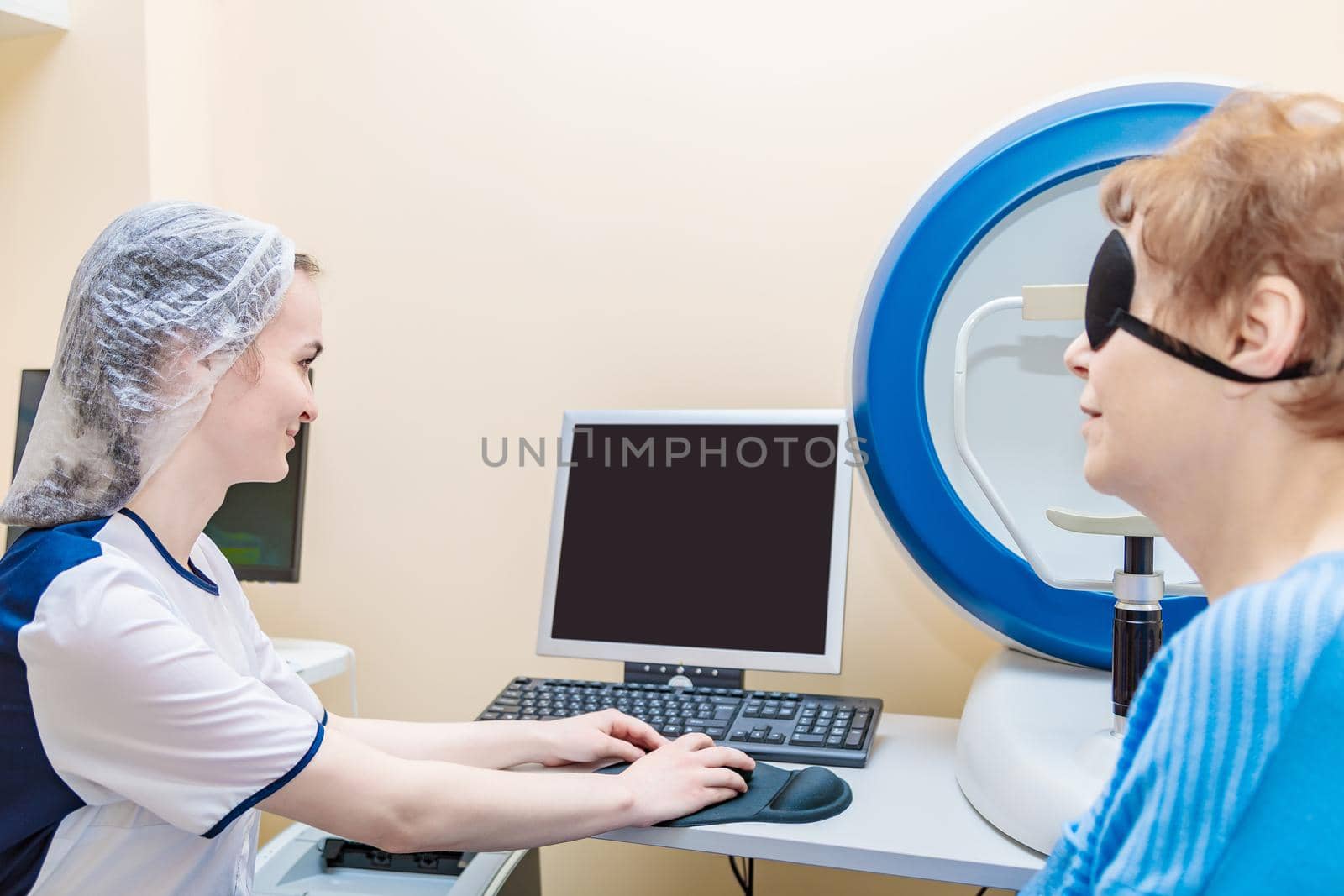 A girl optometrist examines the eyes of a patient using special modern equipment by Yurich32