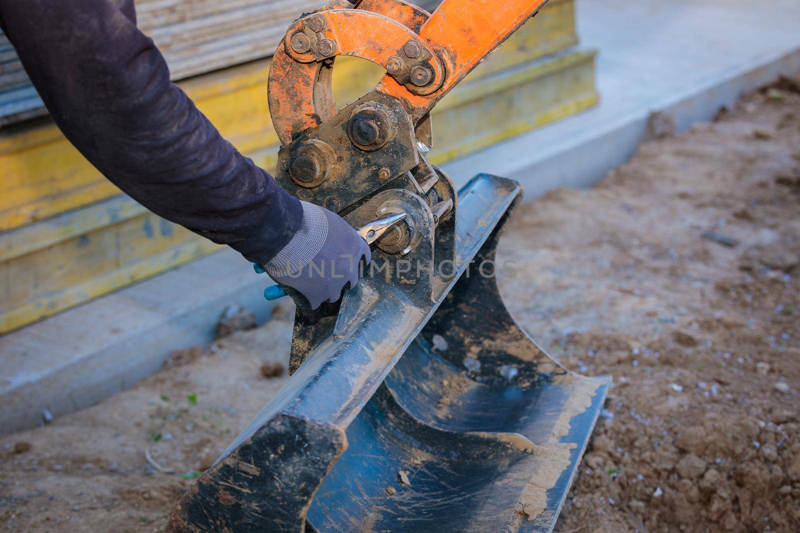 A man repairs a tractor bucket, changes the mounting sleeve. Replacing the nozzle on the tractor boom. Close-up