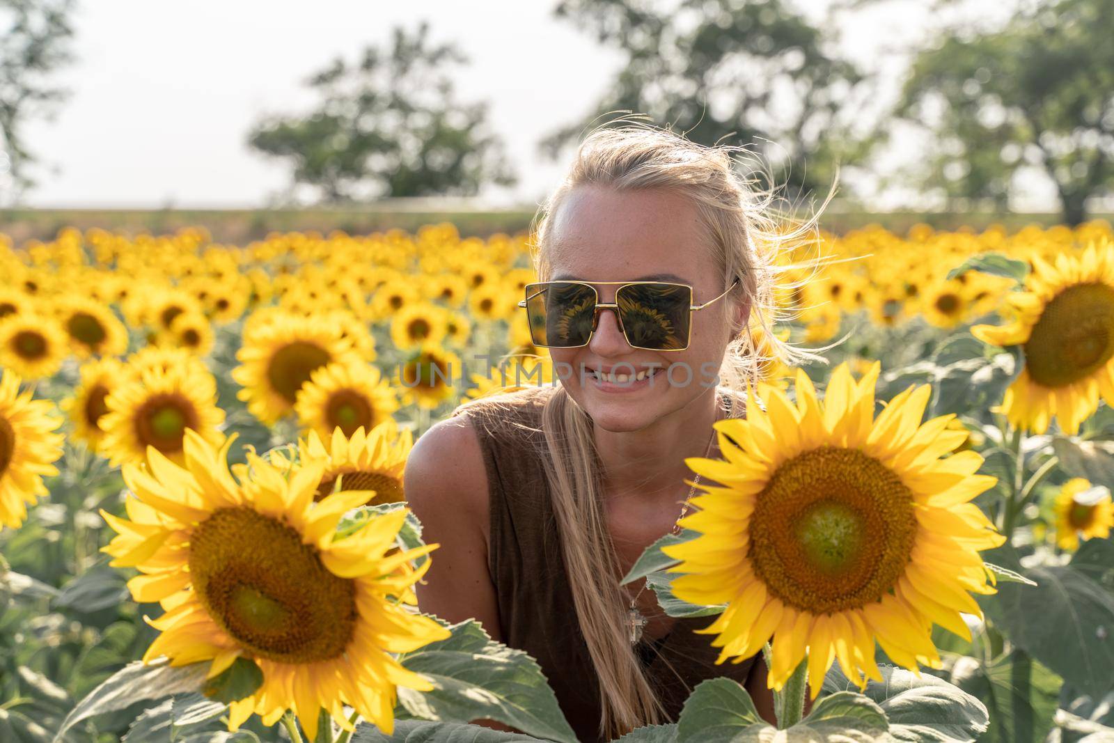 Beautiful woman in sunflower field at sunset enjoying summer nature. Attractive blonde with long healthy hair. by Matiunina