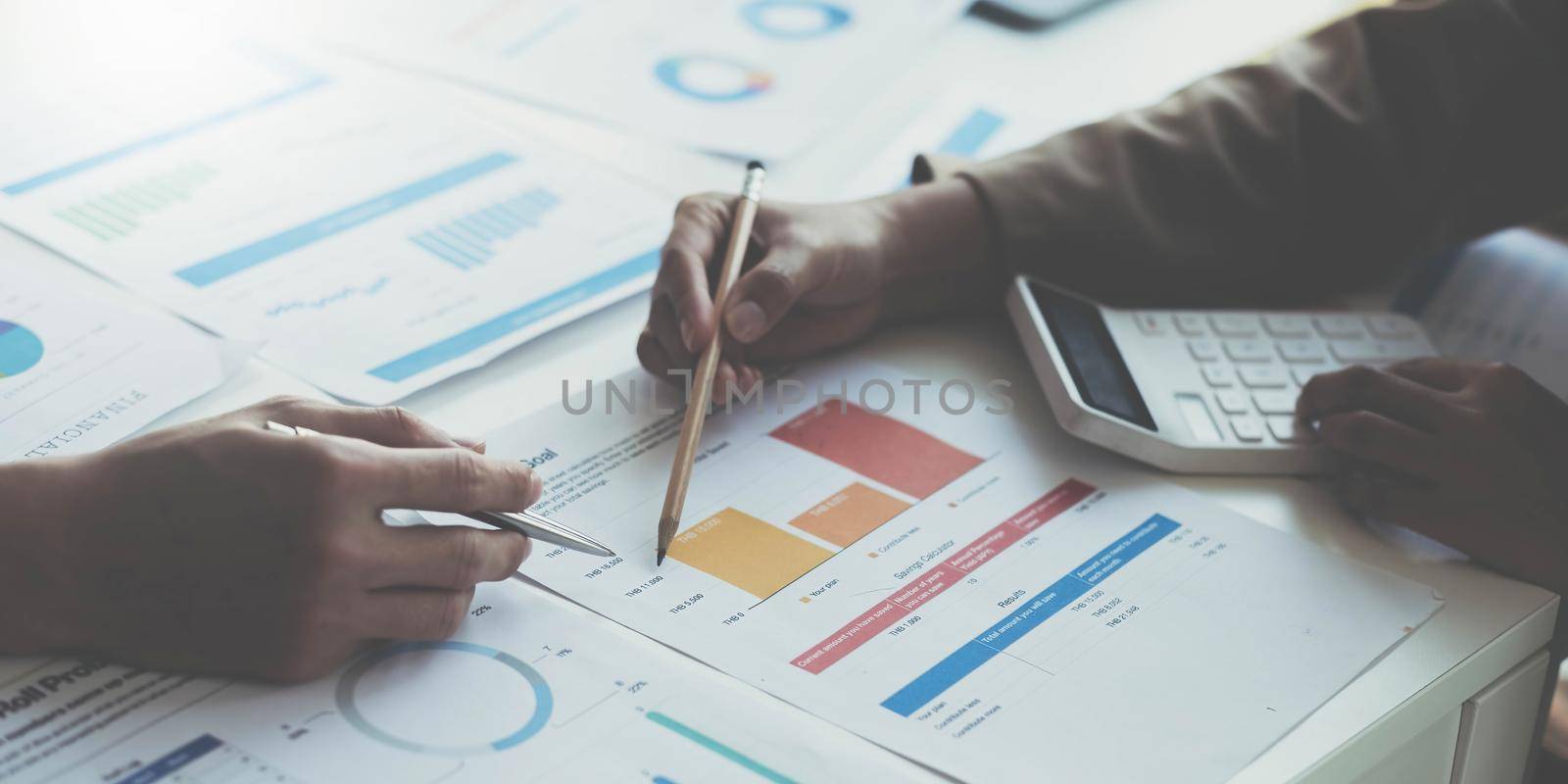 Close up of accountant working and analyzing financial reports project accounting with chart graph and calculator in modern office : finance and business concept. by wichayada