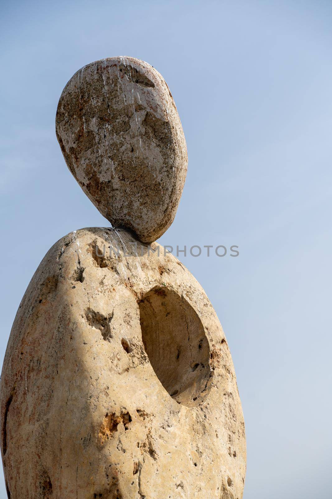 Sculpture symbol made of large pebbles against the blue sky by Matiunina