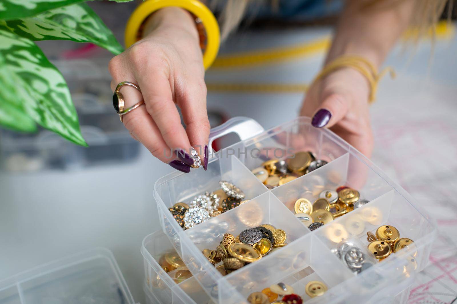 The seamstress chooses from among the many decorative buttons the one that will fit best. At the back of the tailor's workshop.