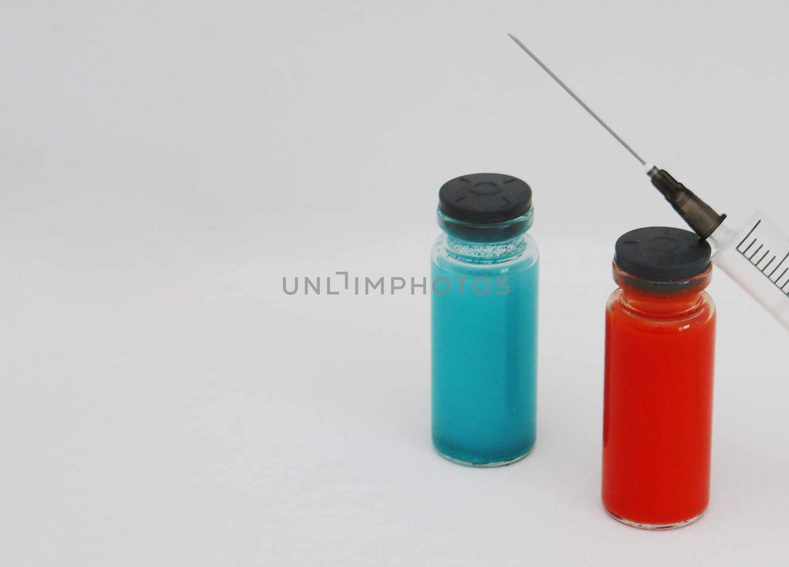 Two Vials of medicine for injection and a syringe. Two ampoules with covid-19 vaccine and a syringe on a white background.