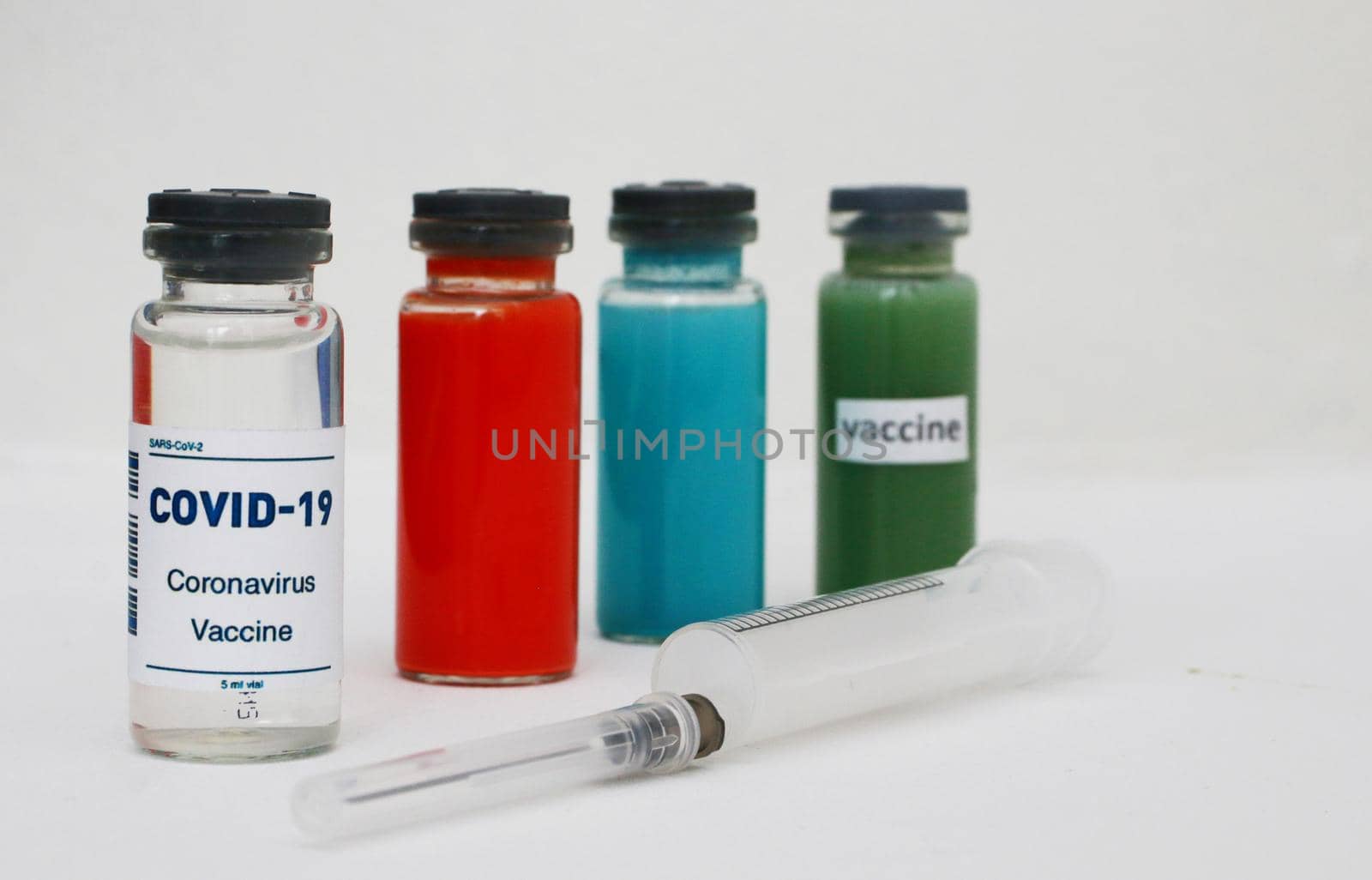 Four ampoules with vaccine and medicines and a syringe on a light background. by gelog67