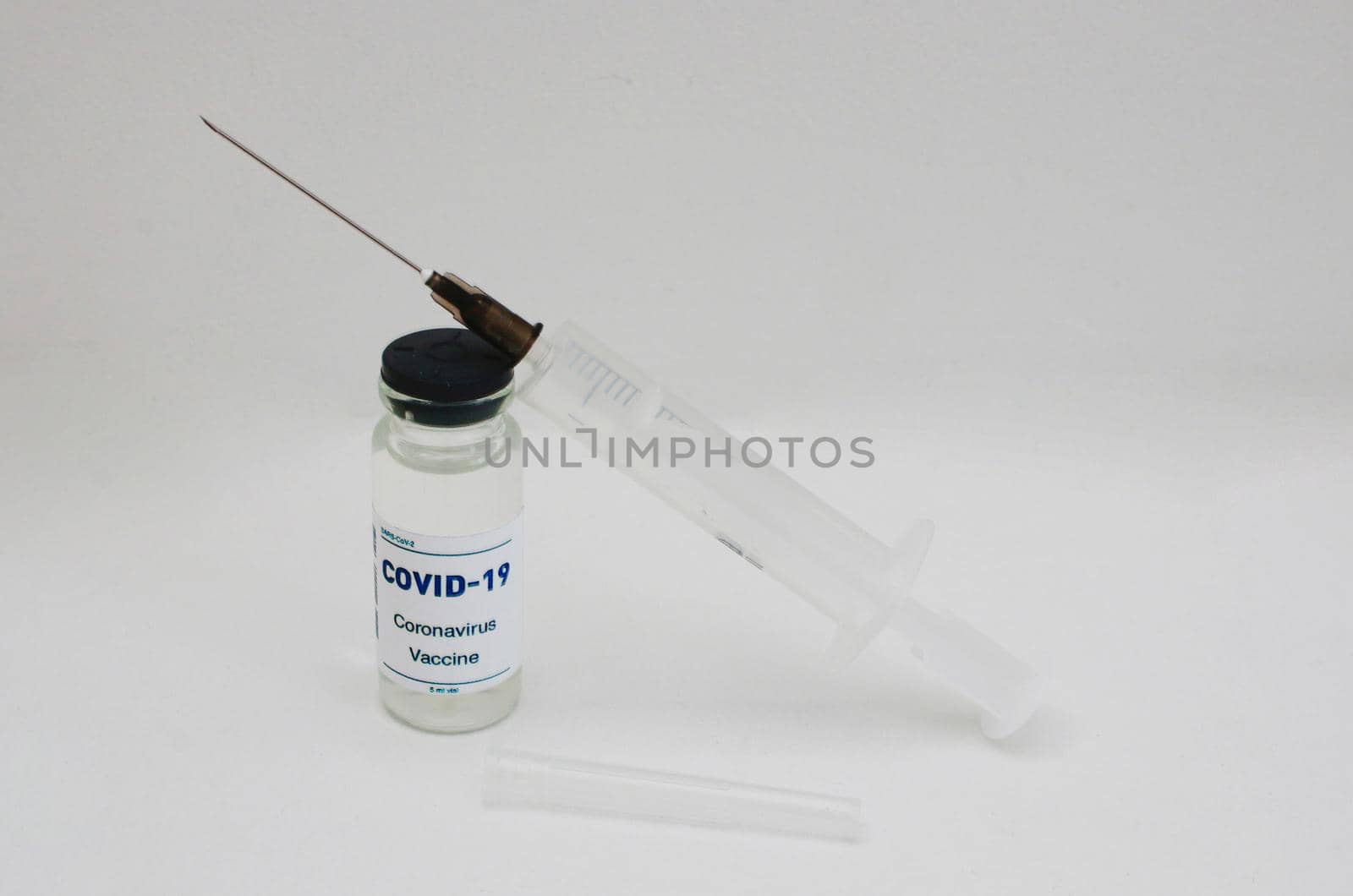 Ampoule with covid-19 vaccine and syringe on a white background.