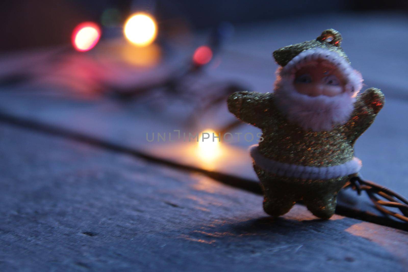 Santa Claus waves his hand affably on a blurred christmas background.