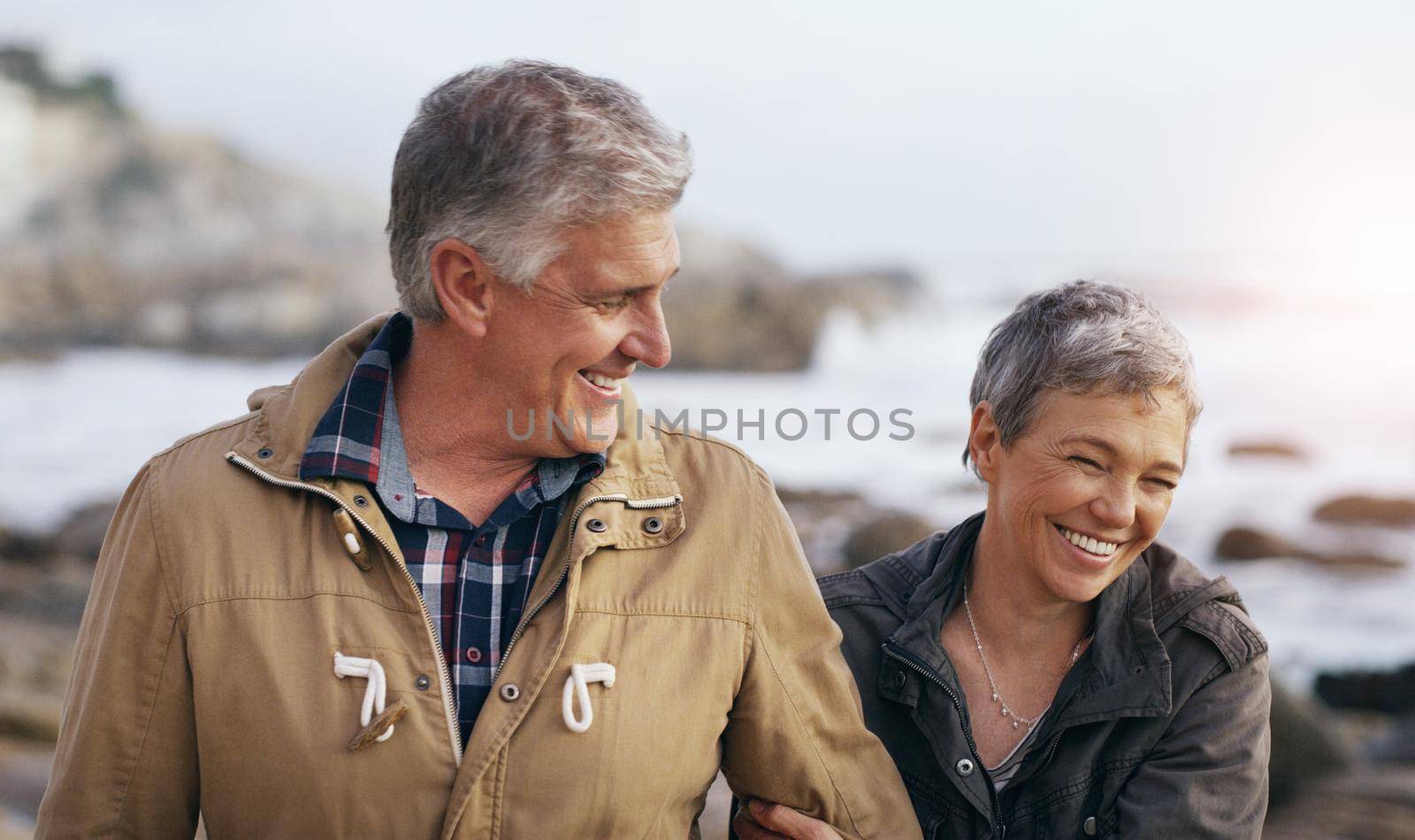 Just like the good old days. a beautiful elderly couple taking a walk at the beach. by YuriArcurs
