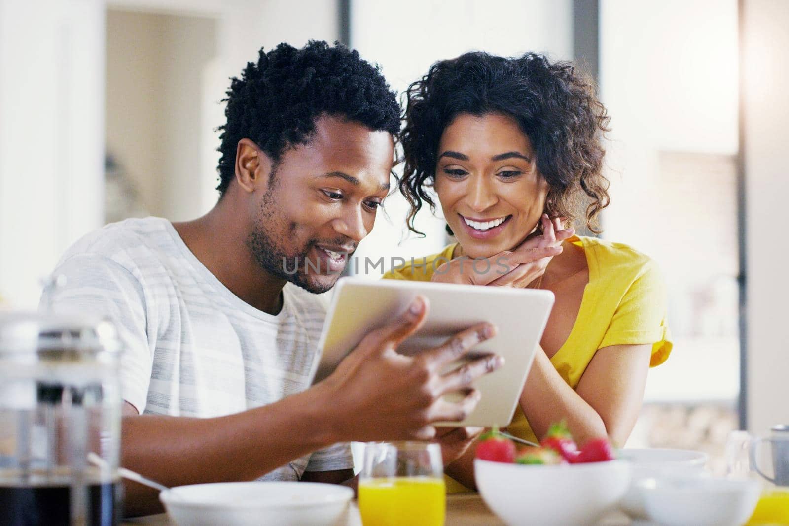 Have a look at this too, its unbelievable. a young couple using a digital tablet together while having breakfast at home