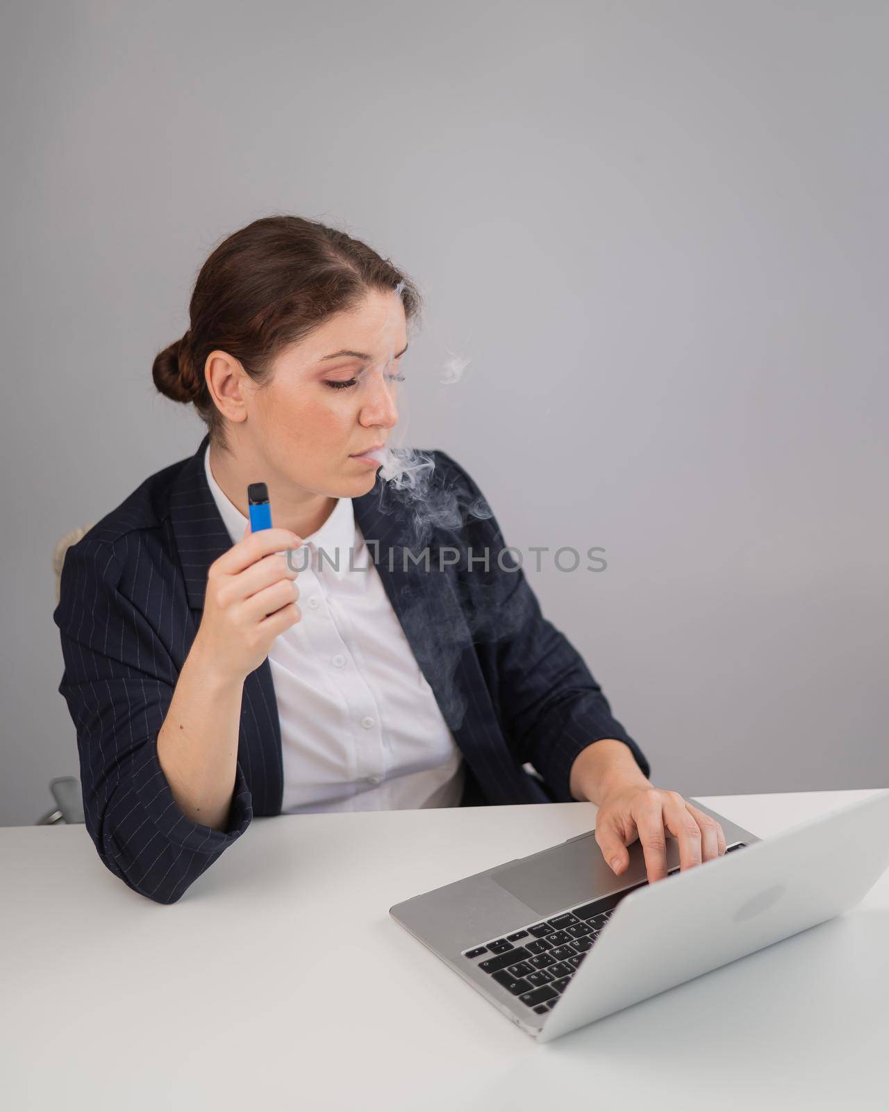 Business woman smoking a disposable vape while sitting at her desk. by mrwed54