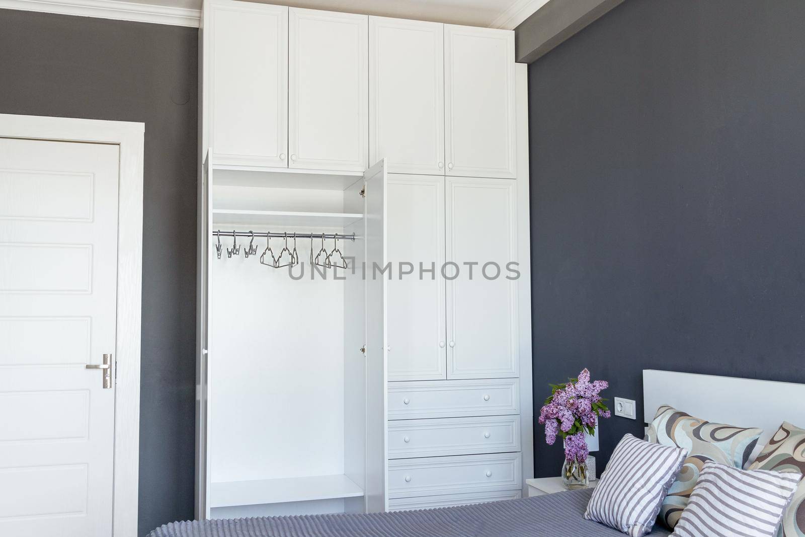 empty white wardrobe with open doors and empty shelves against a gray room. New interior, apartments. The concept of organizing space, order, minimalism, eco-friendly consumption. Cleaning, copy space