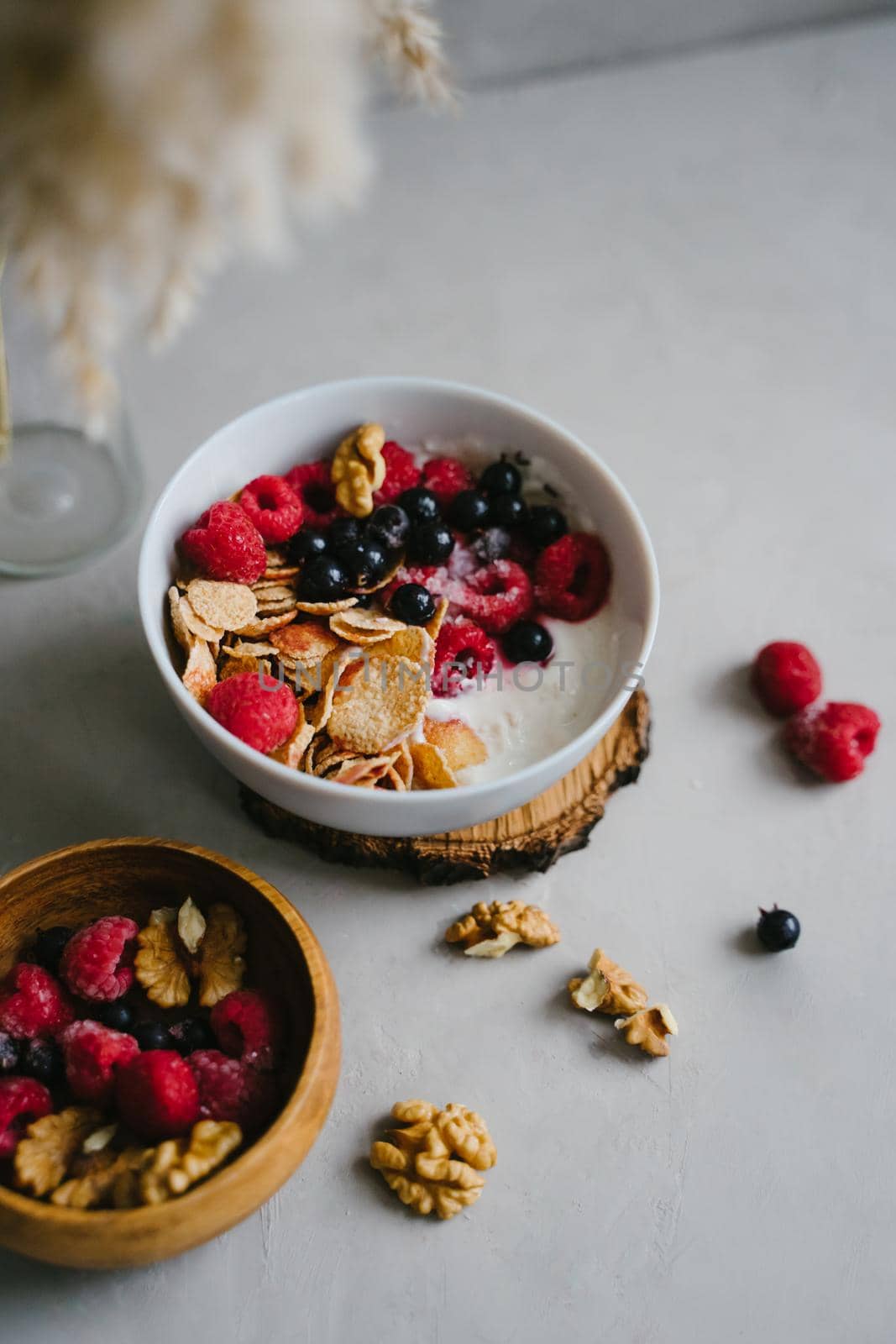 Healthy breakfast with berries. Multi-cereal flakes, natural yogurt, raspberries and black currants, walnuts. Tasty food. Wooden bowl with berries.