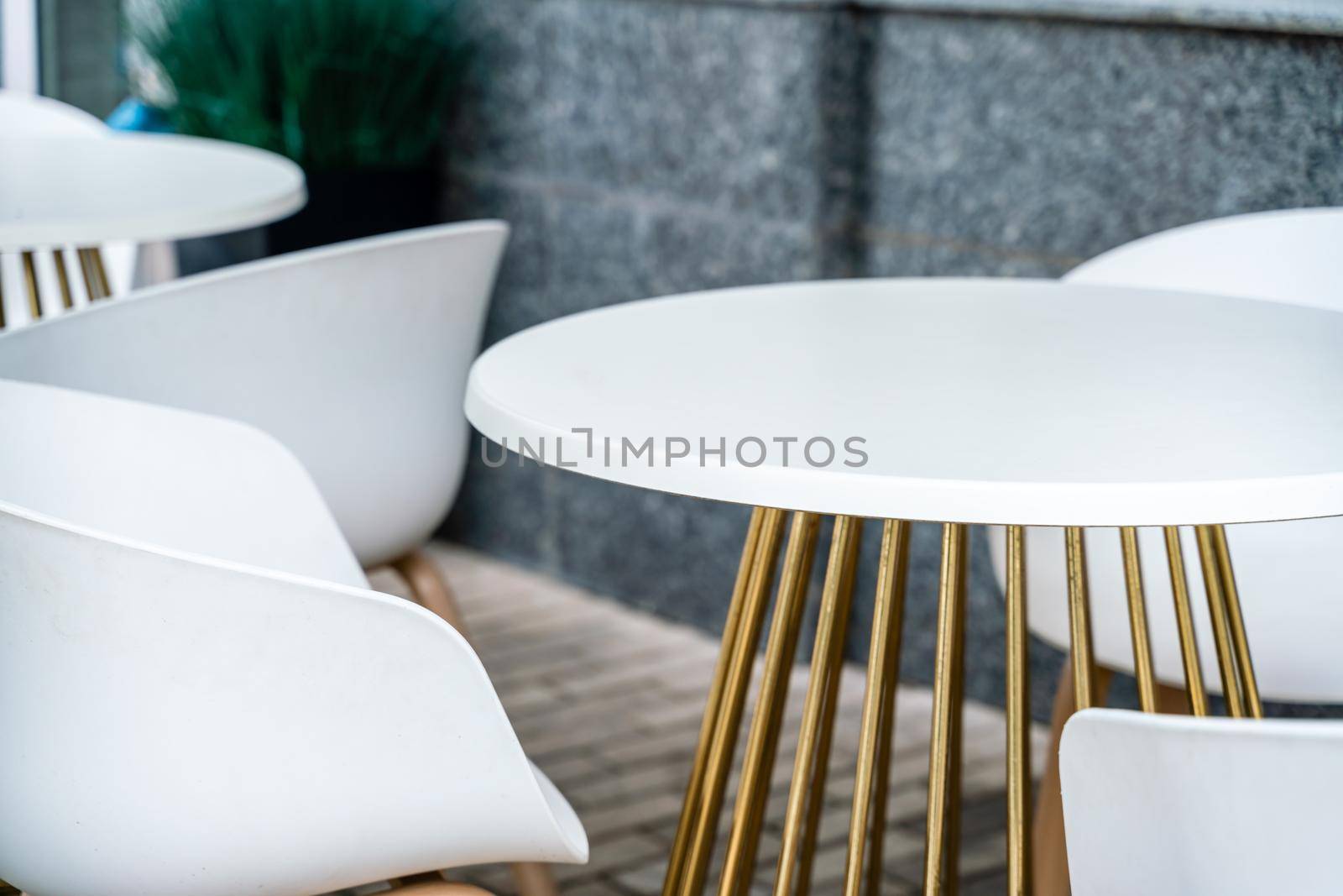 Street cafe with white chairs, green foliage around. Without people, tourism, travel