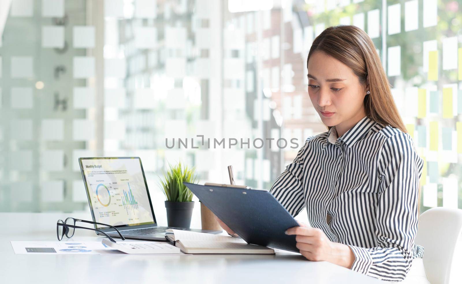 Young Asian businesswoman taking notes using a tablet at the modern office..