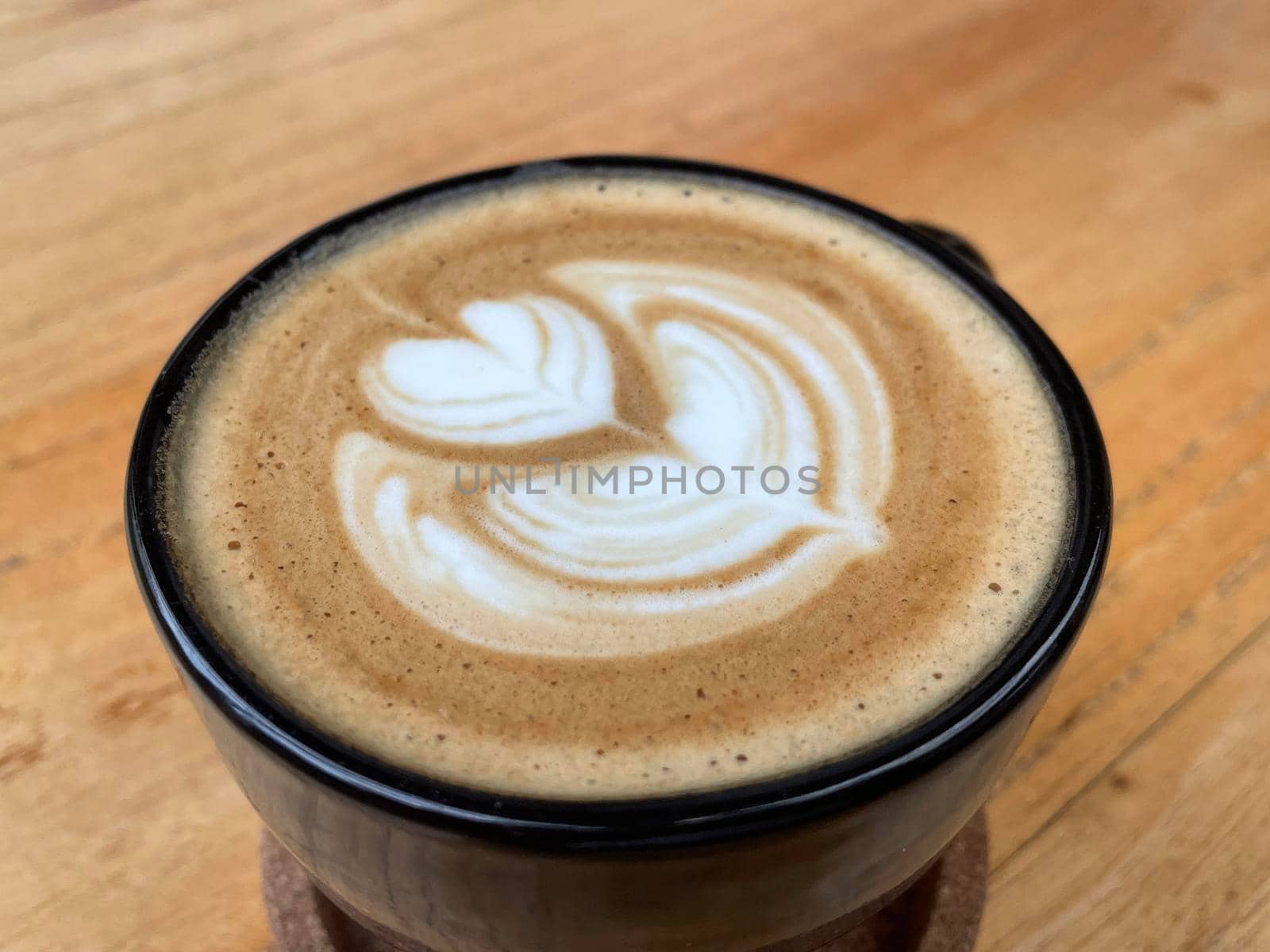 beautiful cup of cappuccino coffee with latte art in the wooden space background by antoksena