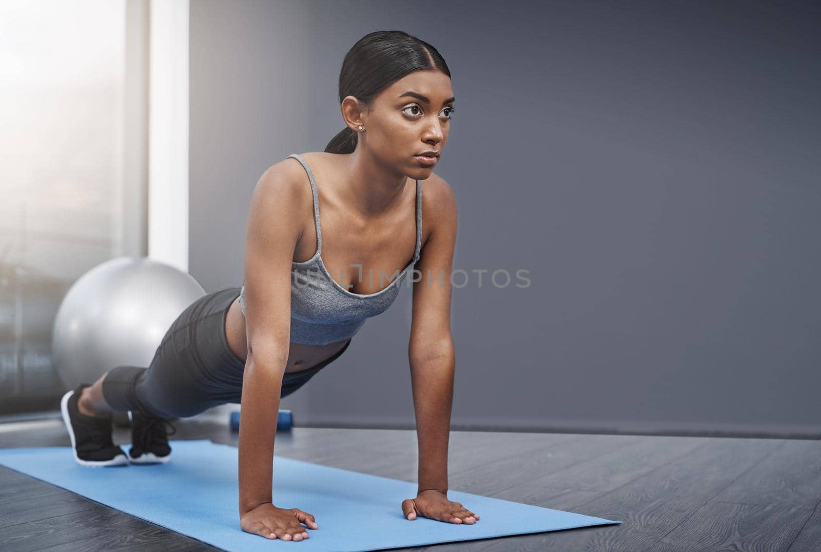 Every decision in the end involves balance and sacrifice. an attractive young woman busy doing stretching exercises on her gym mat at home. by YuriArcurs