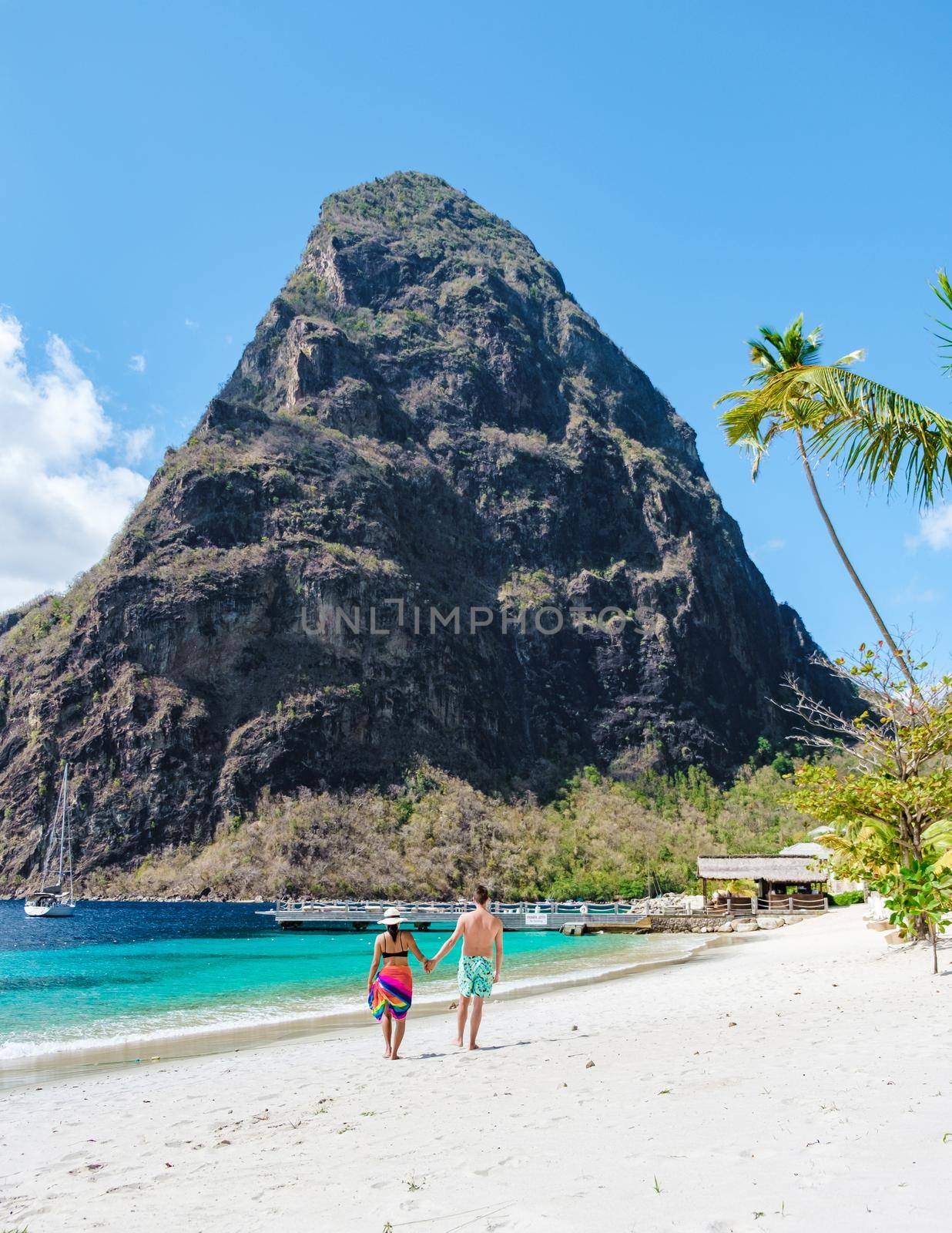 couple walking on the beach during summer vacation on a sunny day, men and woman on vacation at the tropical Island of Saint Lucia Caribbean. Sugar beach St Lucia Caribbean