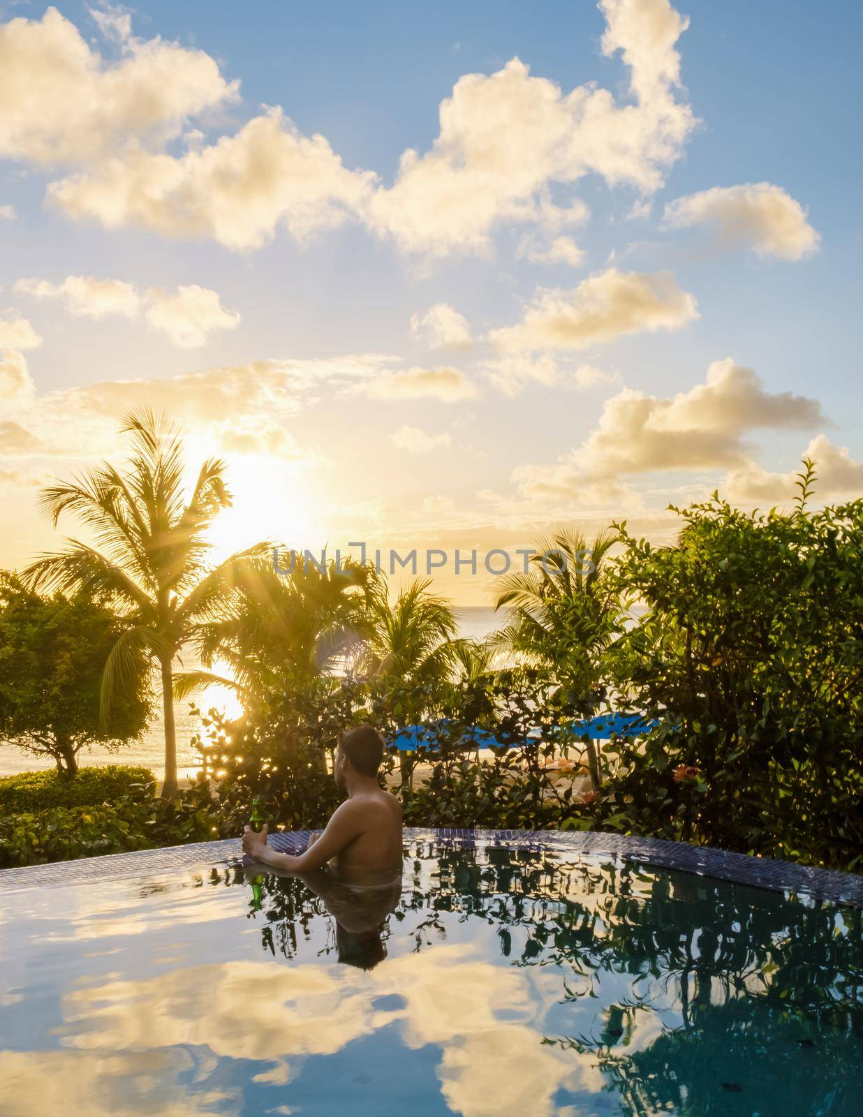 Young men in a swim shorts at Saint Lucia Caribbean, men at infinity pool during sunset. man in a swim short at the pool