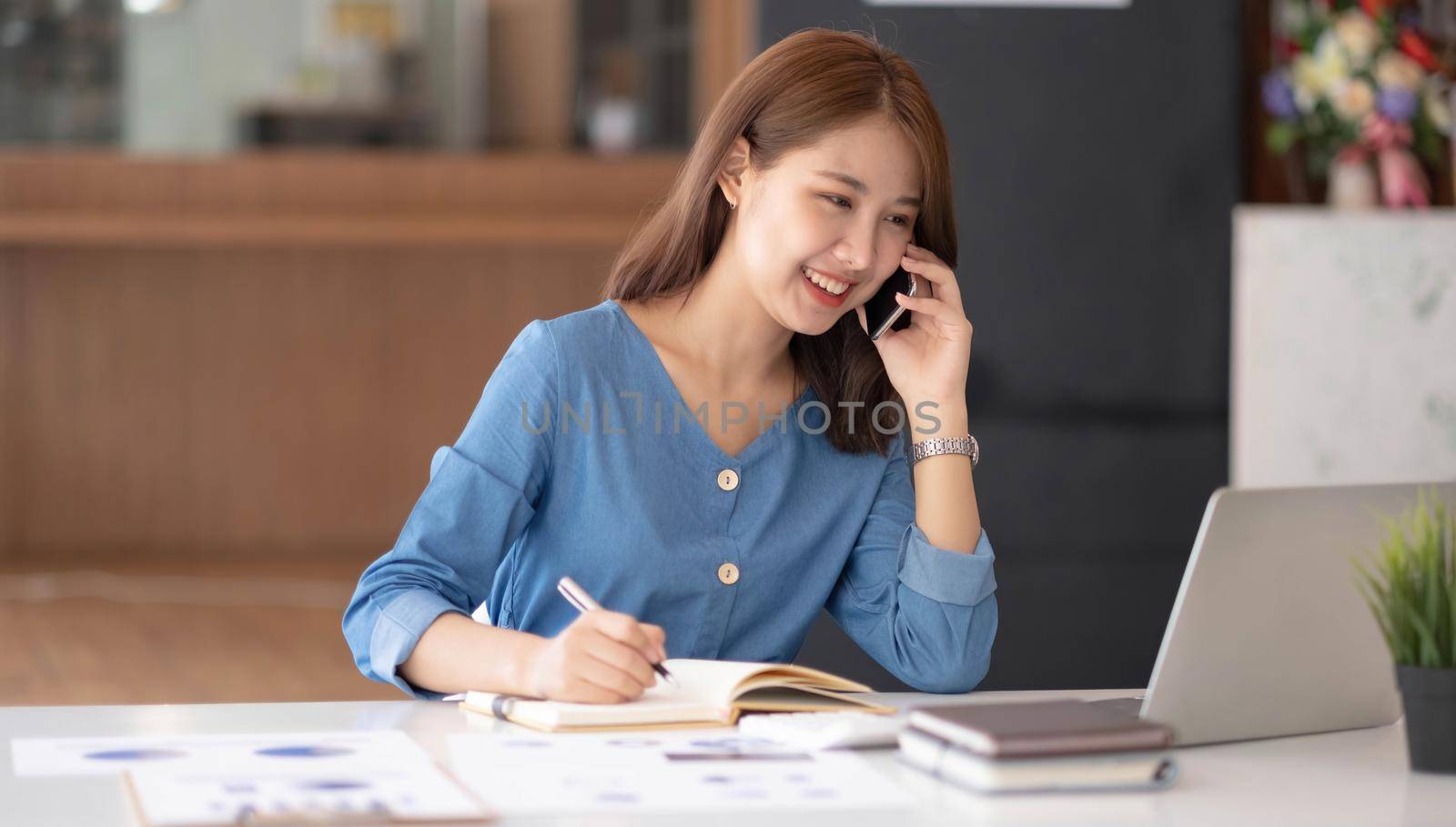 Asian businesswoman in formal suit in office happy and cheerful during using smartphone and working.