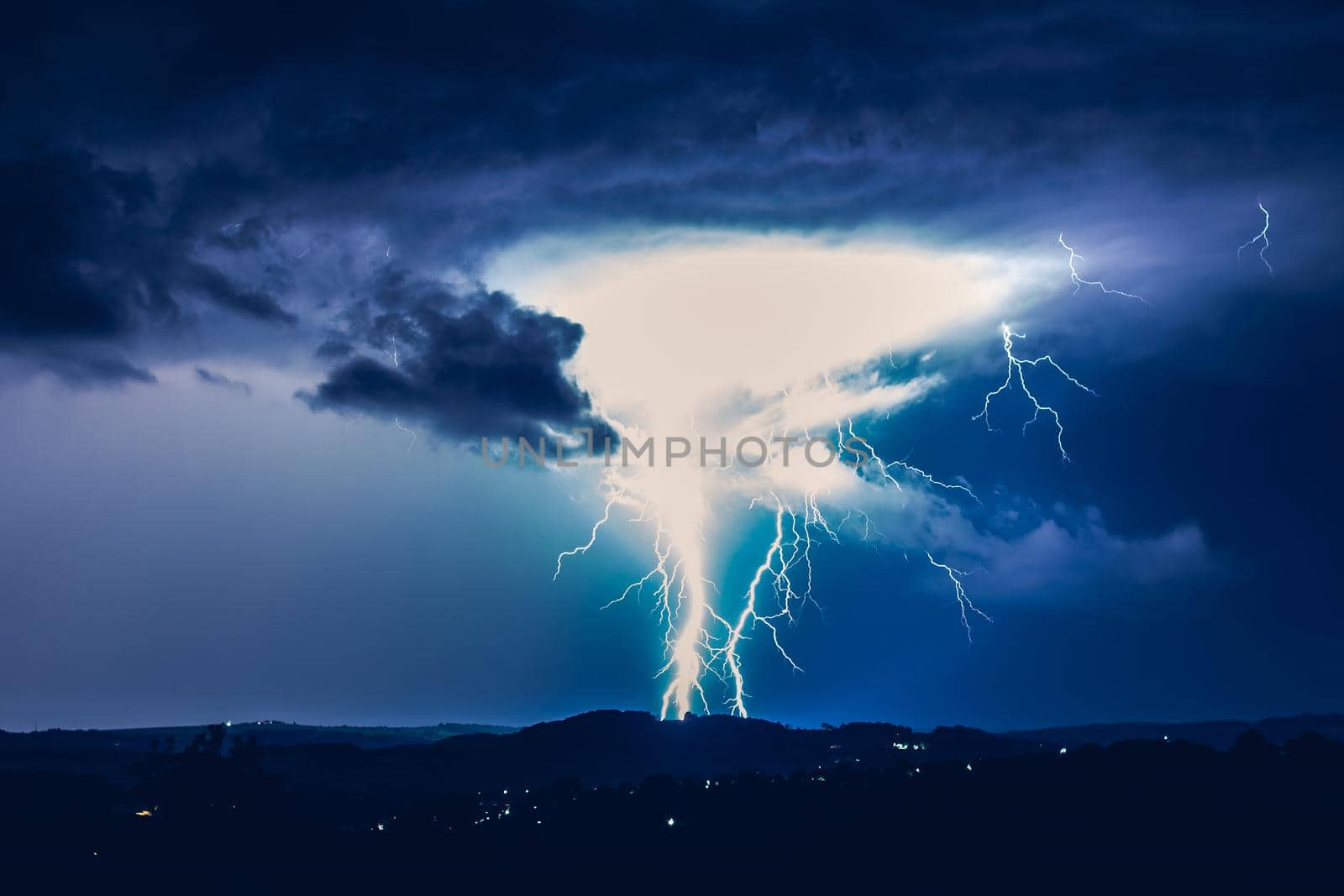 Night landscape on a background of thunderstorms. Rural silhouette and clouds with lightning flashes