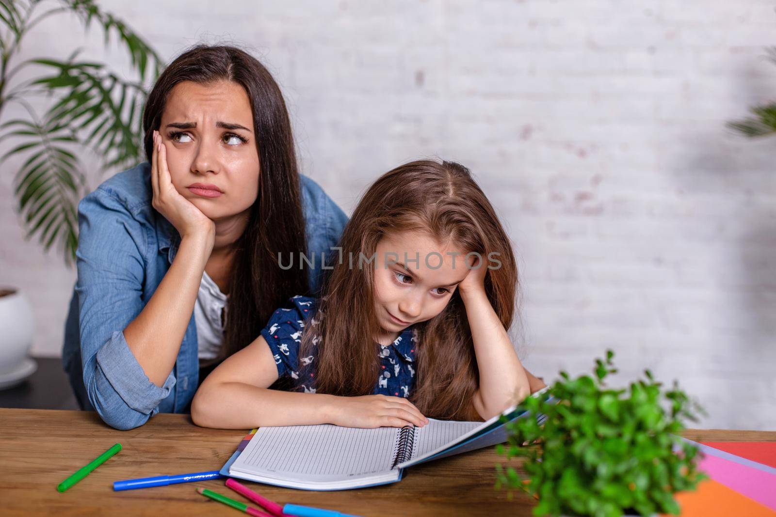 Mother becoming frustrated with daughter whilst doing homework sitting at the table at home in learning difficulties homework. Parenting and education concept