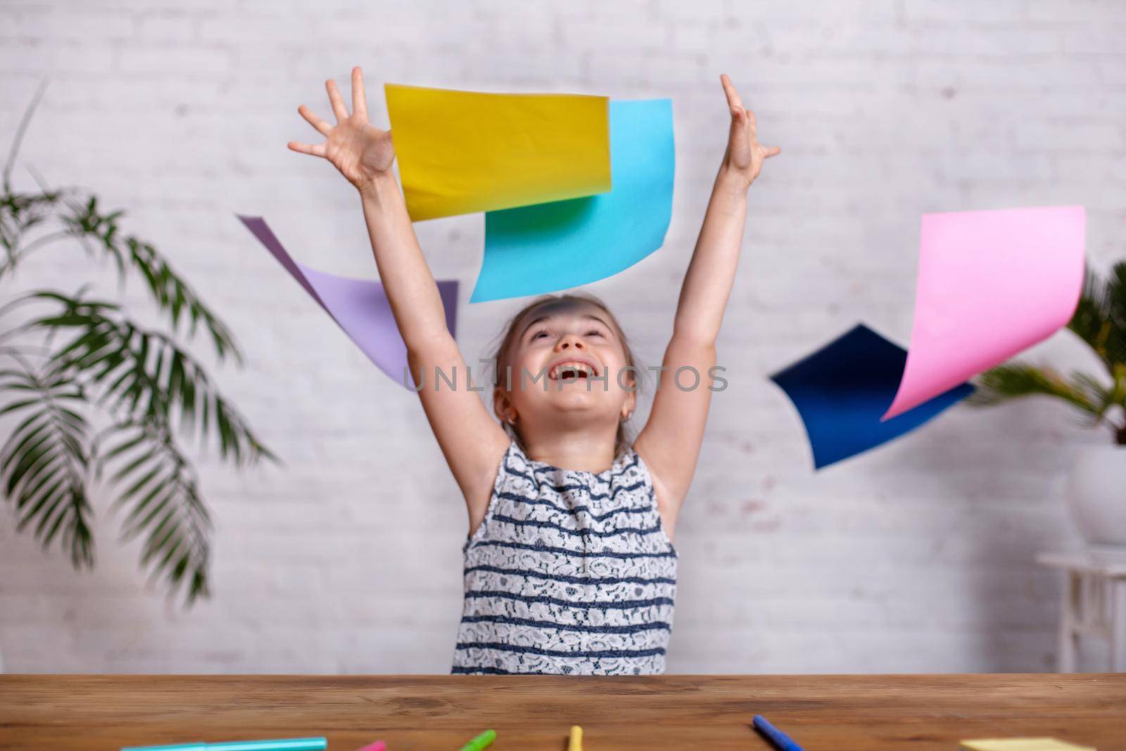 Motion blur. Cute little girl at the table with the colored paper