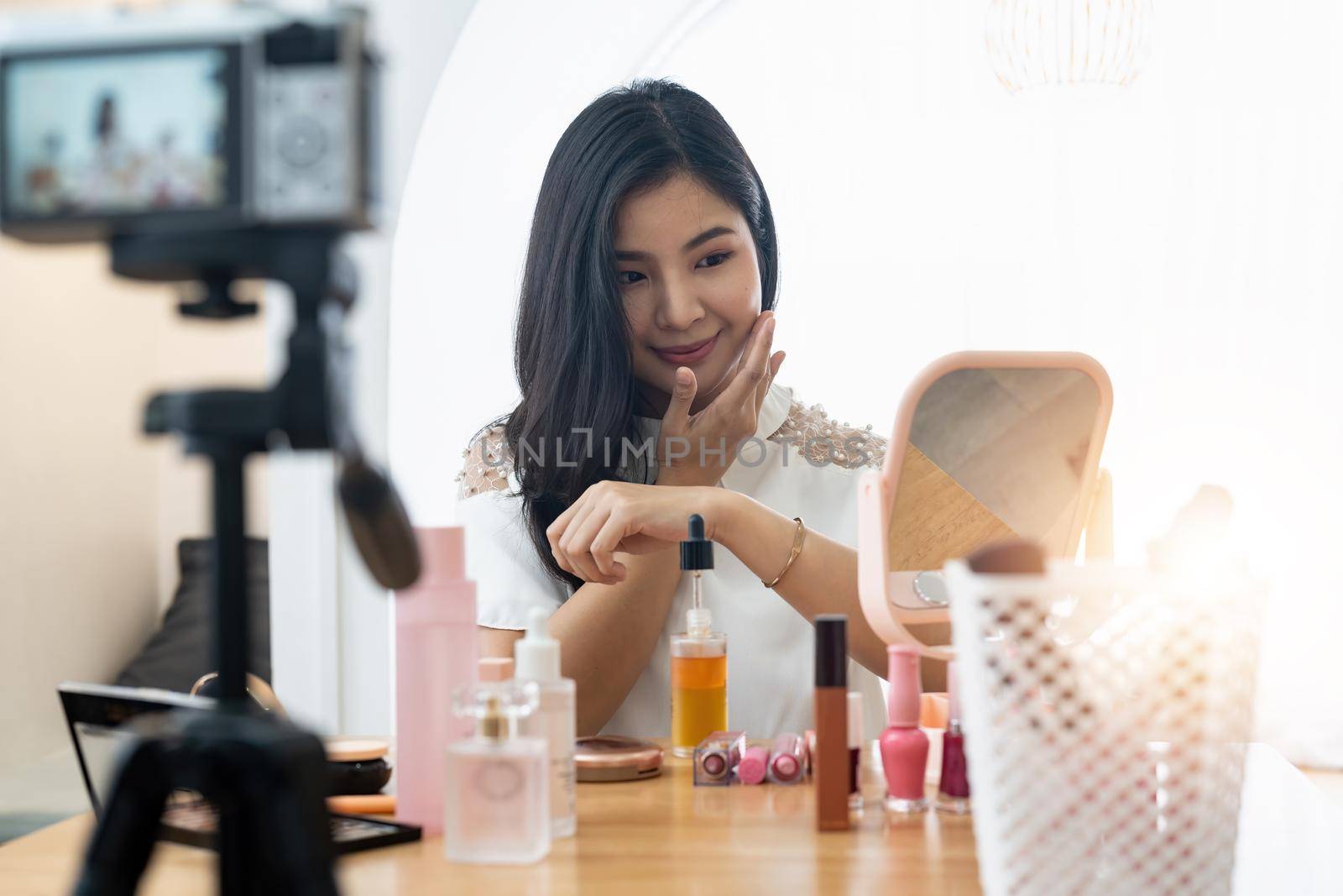 Young beautiful Asian woman and professional beauty make up artist vlogger or blogger recording makeup tutorial to share on website or social media. Business online influencer on social media concept