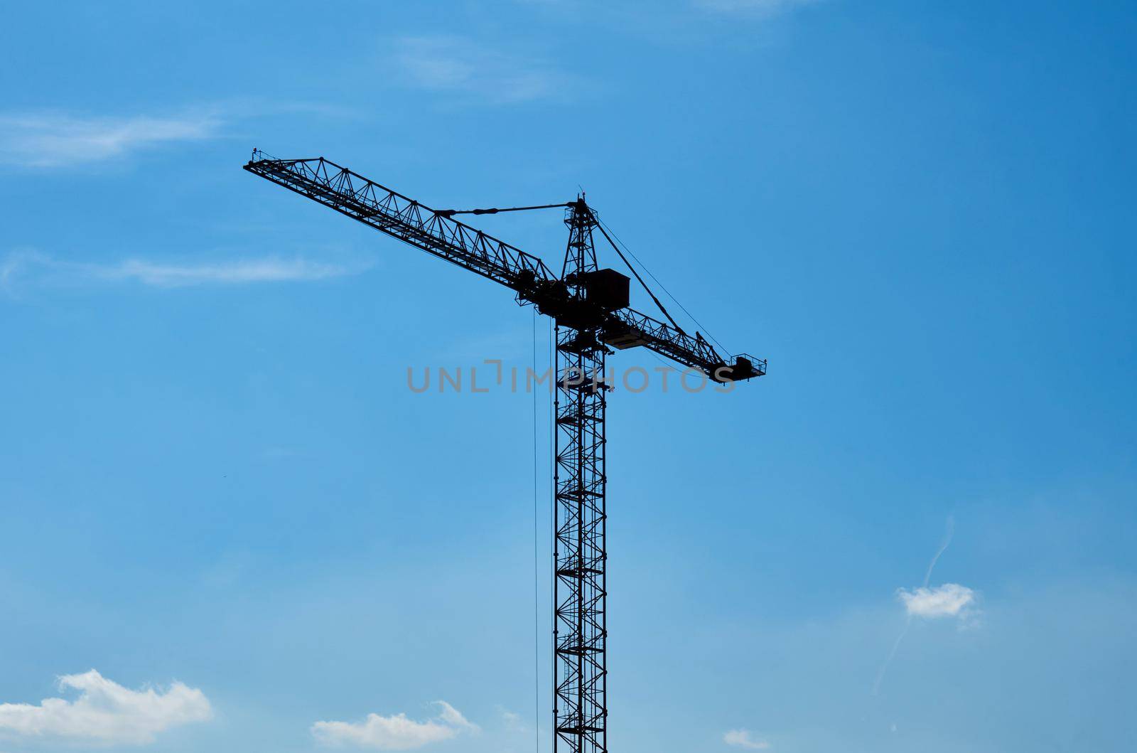 a large, tall machine used for moving heavy objects by suspending them from a projecting arm or beam. Construction high crane and blue clear sky. High quality photo