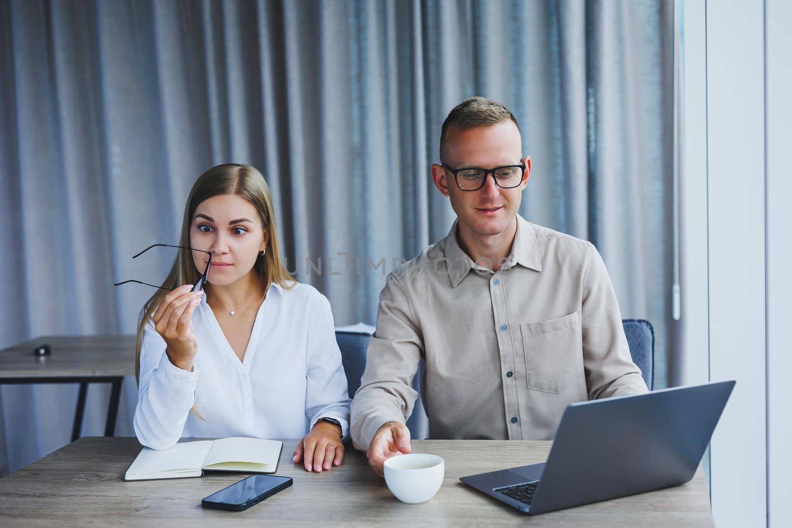 Young business team, male and female colleagues talking at work, discussing a new project with a laptop, young executives having a friendly conversation, collaborating in teamwork in the office