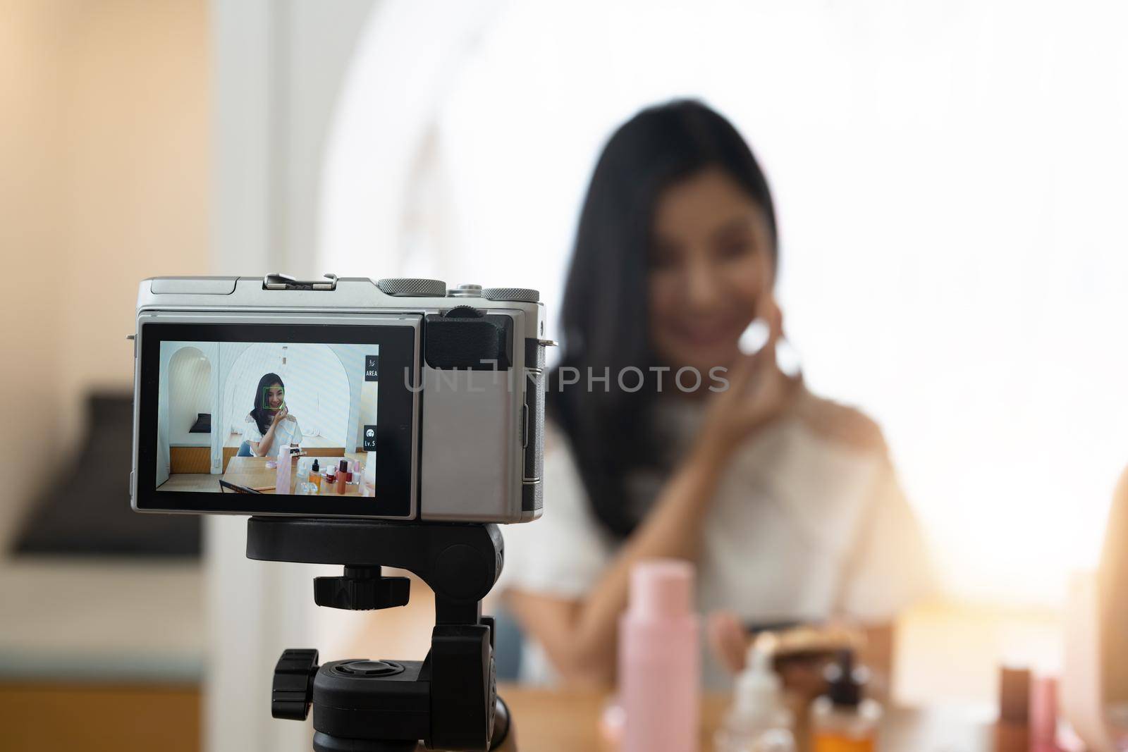 Young beautiful Asian woman and professional beauty make up artist vlogger or blogger recording makeup tutorial to share on website or social media. Business online influencer on social media concept.