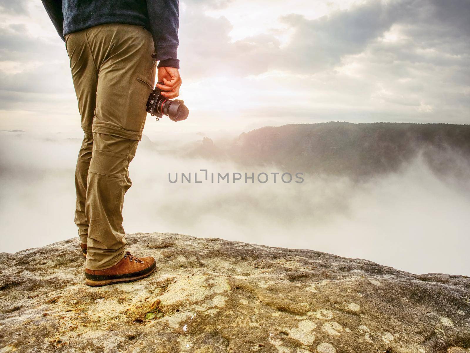 Photographer on mountain cliff looking into mist. Hiker will take picture by rdonar2