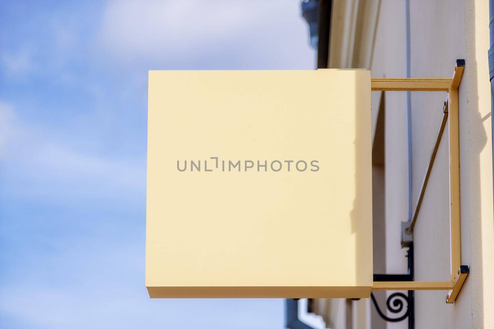 square yellow signboard made of metal on a sunny day, close-up against the blue sky. Sign mockup for a beauty salon, restaurant, hotel or other facility. Urban landscape. copy space