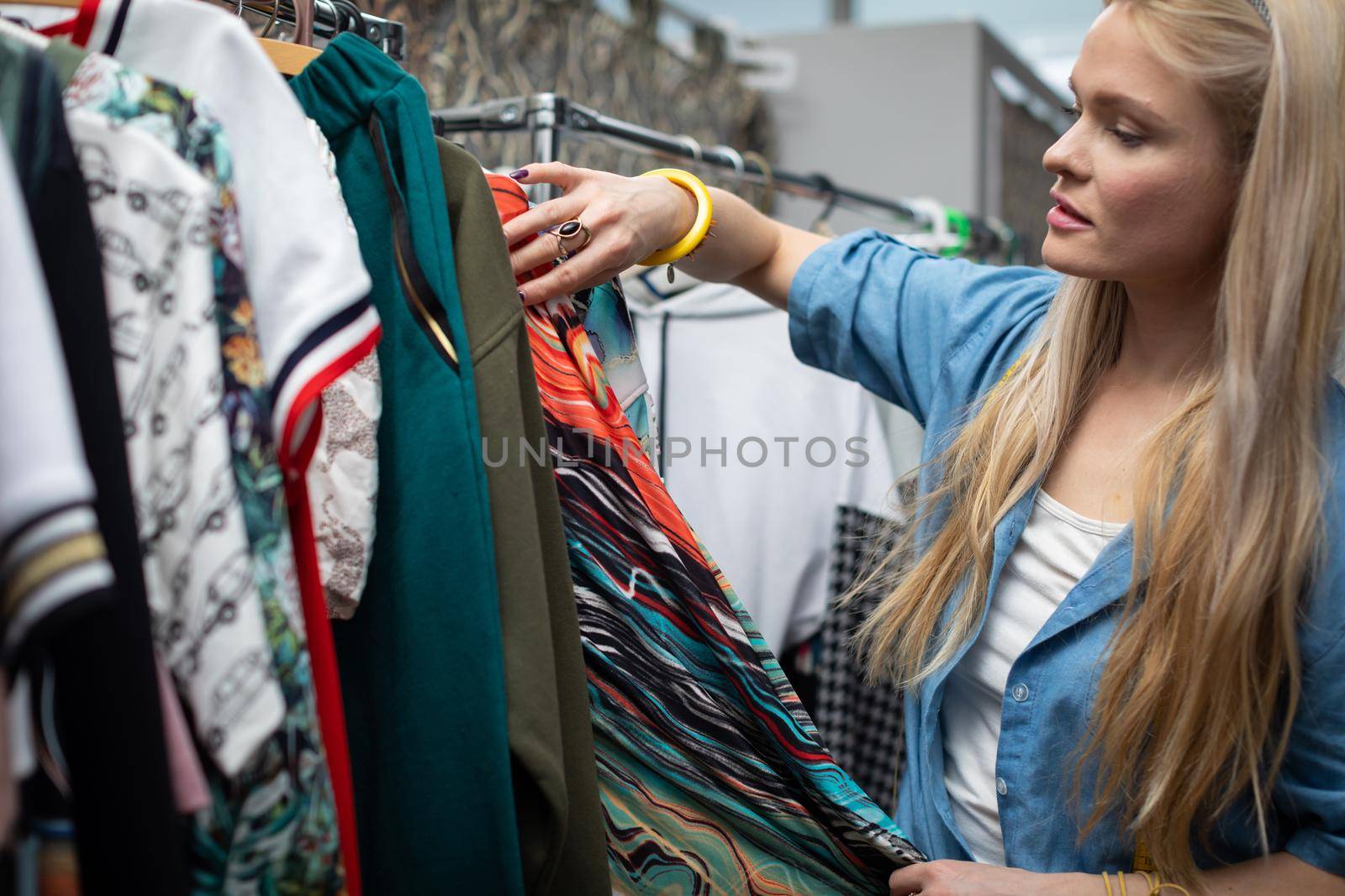 The girl browses through various clothes hanging on hangers. by fotodrobik